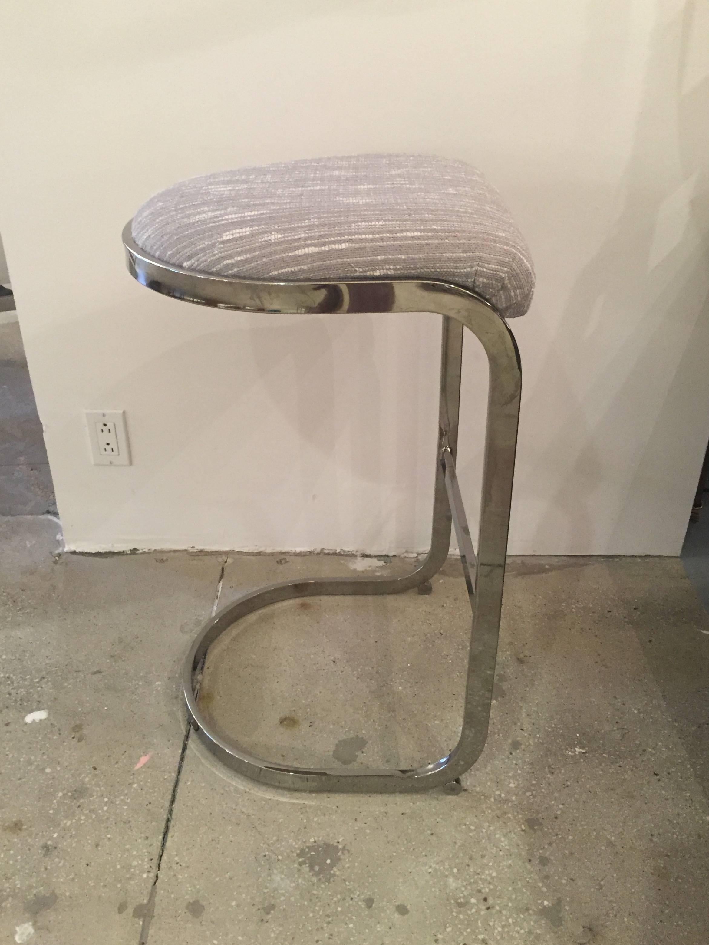 A pair of chrome bar stools in the style of Milo Baughman. USA, circa 1970. Chrome frame with gray/beige striated fabric. 

Dimensions: 
Seat height 30 inches