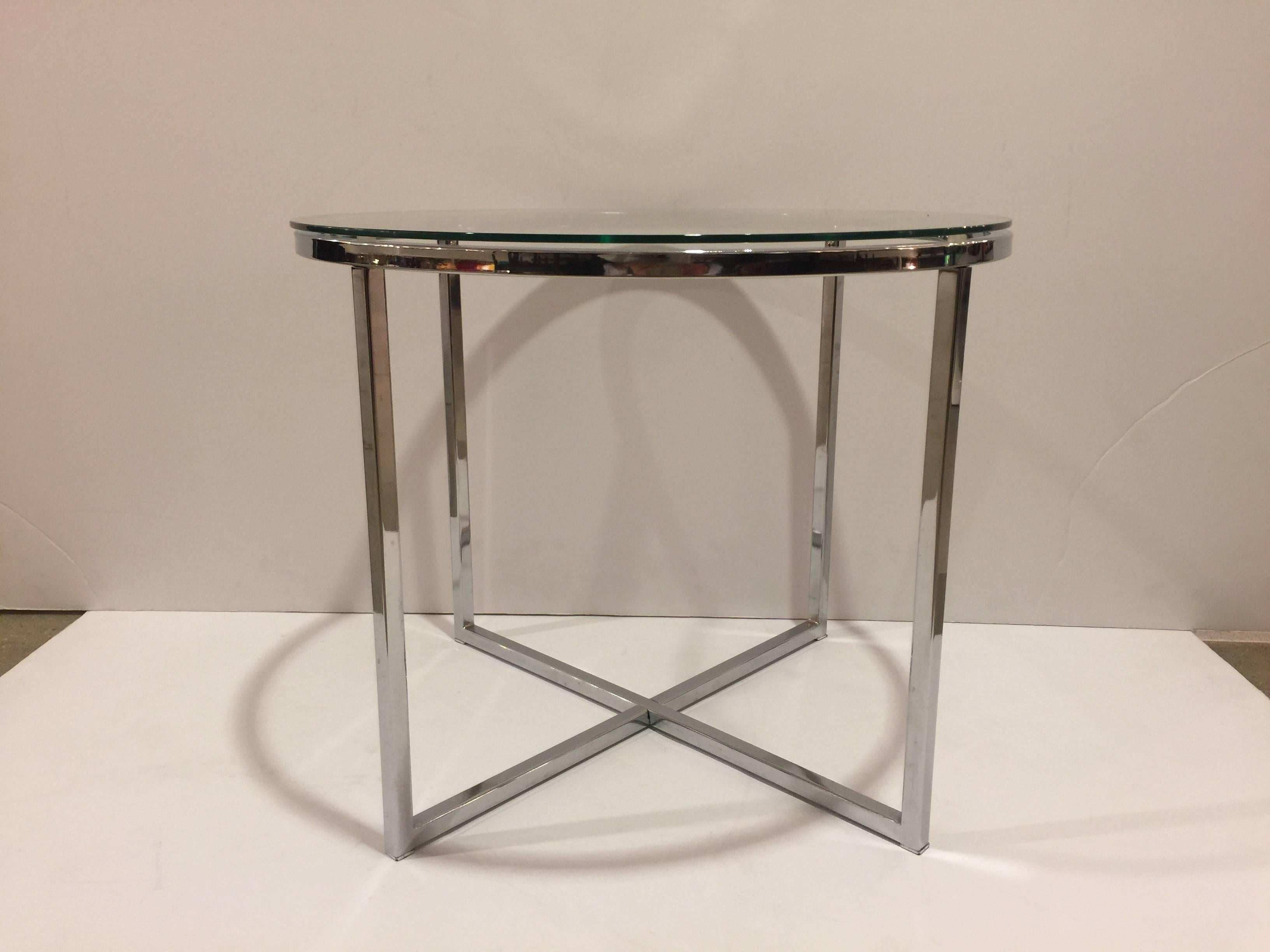A polished chrome round end table with round glass top and cross-leg base attributed to Milo Baughman. 

USA , circa 1970. 

Unsigned. 

Measures 21.5 inches wide by 17 inches tall.

