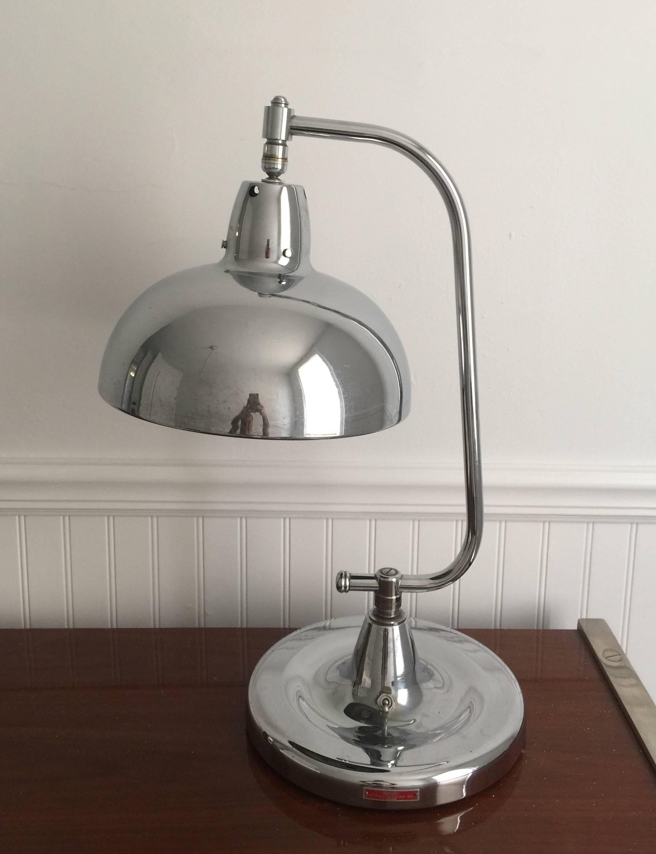 A polished chrome jeweler's lamp wth adjustable shade and pivoting base, USA, circa 1940. Signed.

Dimensions:
22 inch height
10.5 inch base.