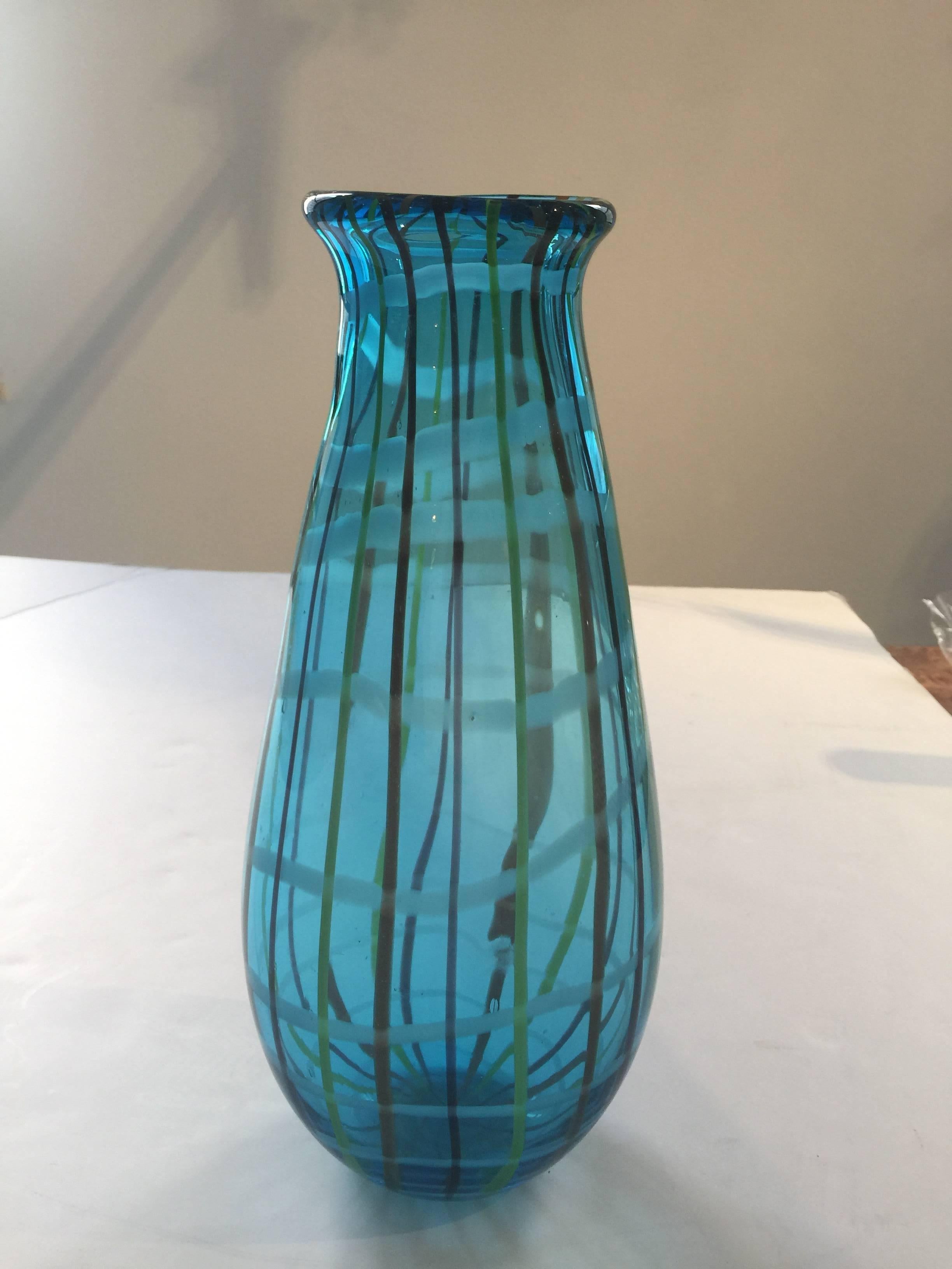 A thick glass vase in blue-green with an applied multi-color striped pattern, Italy, circa 1970.
Dimensions: 15