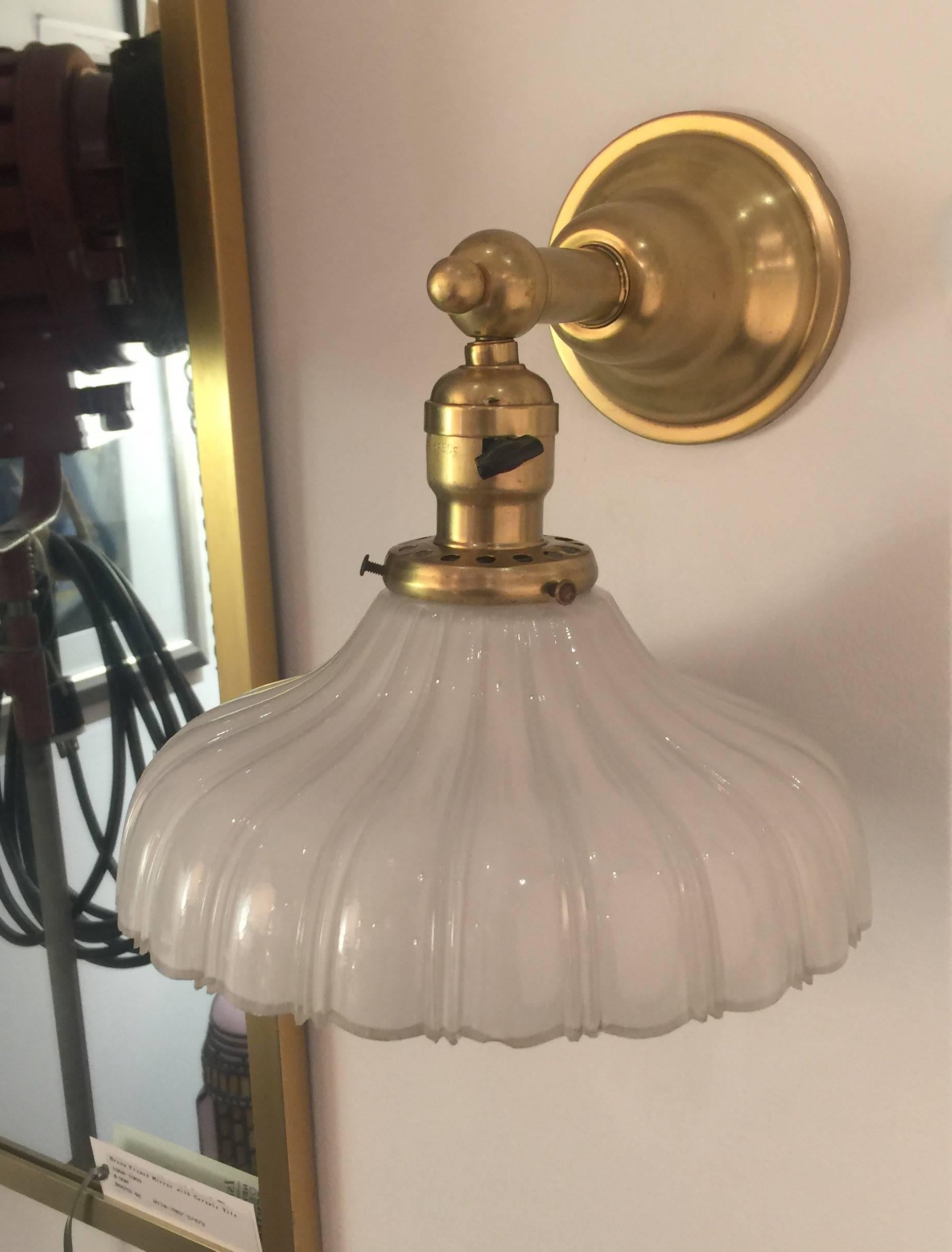 Pair of vintage brass wall lights with period scalloped milk glass shades, USA, circa 1930. Wall lights and shades are both vintage.

Restored and rewired with new sockets and wiring. Original vintage wall bracket, black on/off switch and shade.