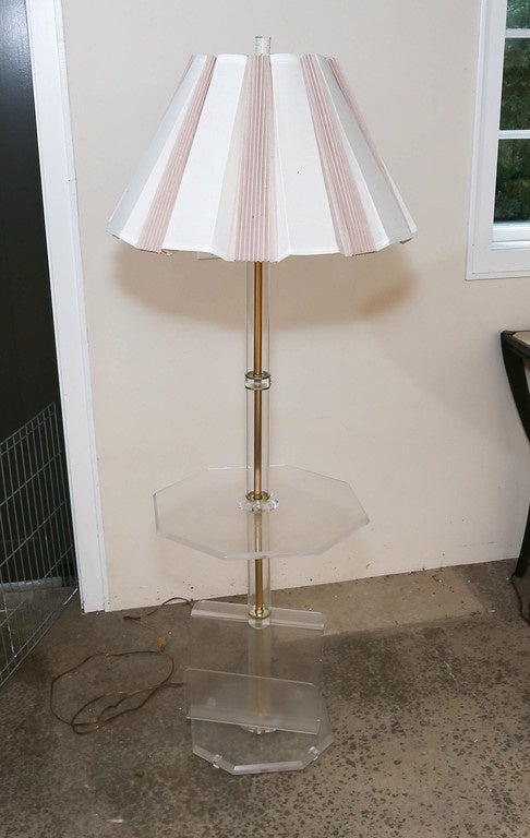 Unusual Mid-Century Lucite floor lamp with attached magazine rack. The lamp has the original custom-made paper shade. The octagonal table is 17.5 in diameter. Both the table and the base are beveled Lucite. The finial is also vintage Lucite.