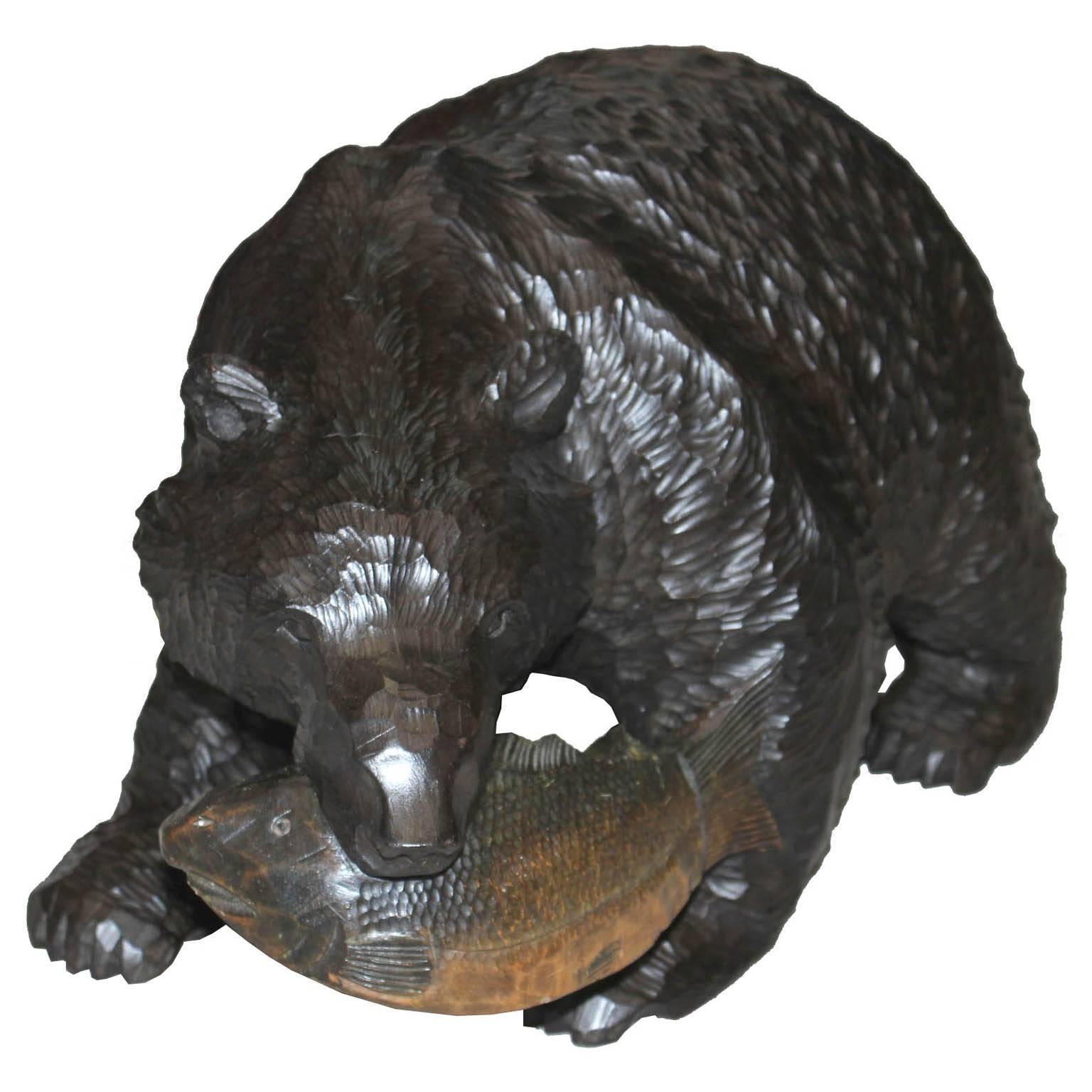 Vintage Japanese carved wood bear carrying a salmon in his mouth. Hand-carved by the Ainu (indigenous people of Japan) from the island of Hokkaido. Taisho period, circa 1920s. Sugi (cedar wood).