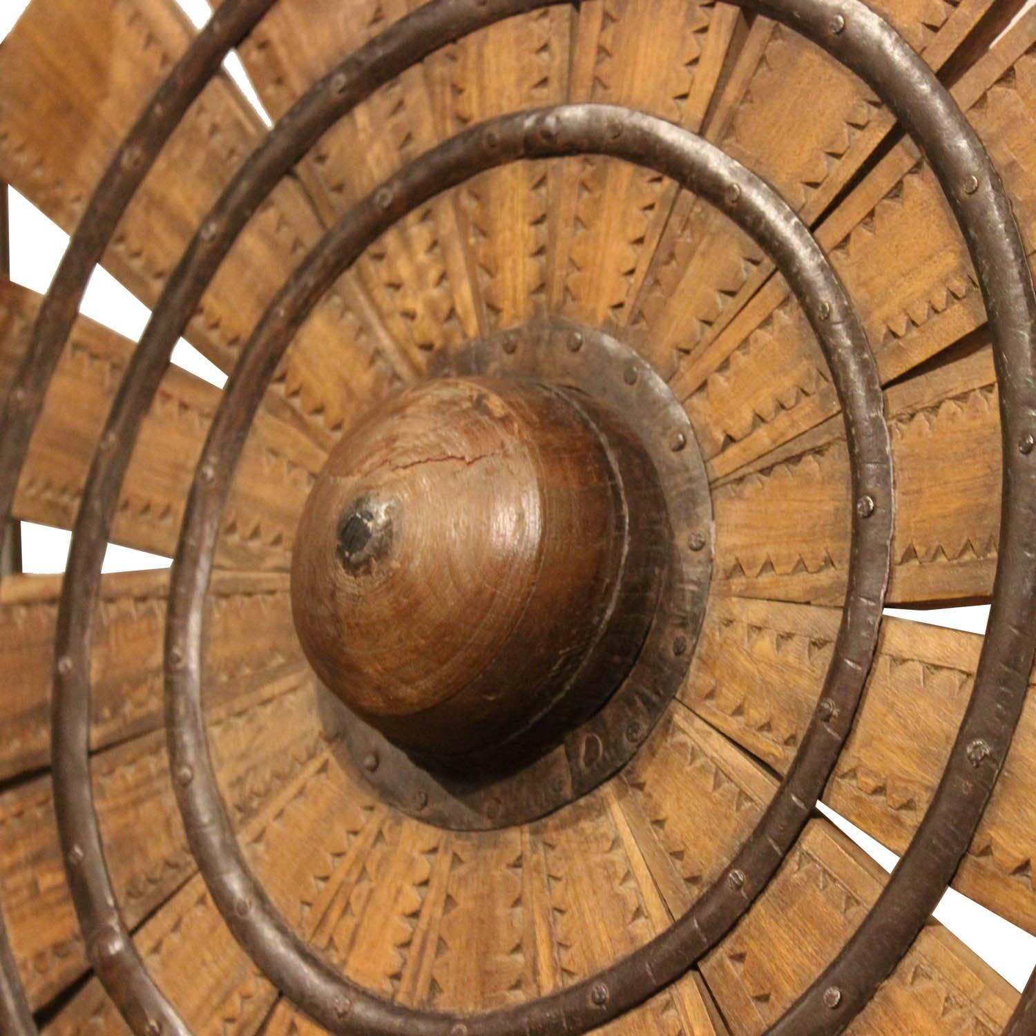 Vintage teak wood weaving wheel from northern India. With iron hardmounts and mounted on a black metal Stand. Unusual accessory can be placed on a bookshelf or on a console table.