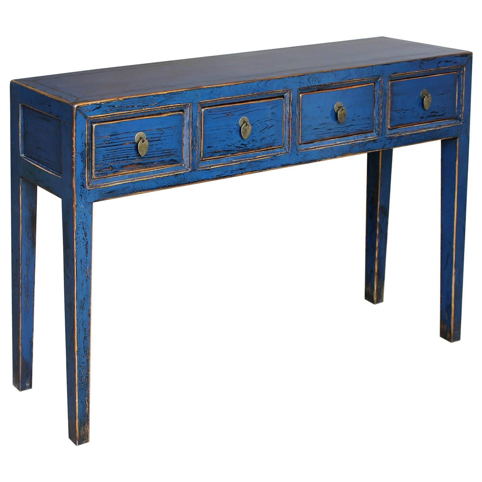 Vibrant blue four-drawer console table with exposed wood edges and clean lines is a statement piece in a contemporary home.  Bring color into your living room by placing this console against a wall or behind a sofa.
