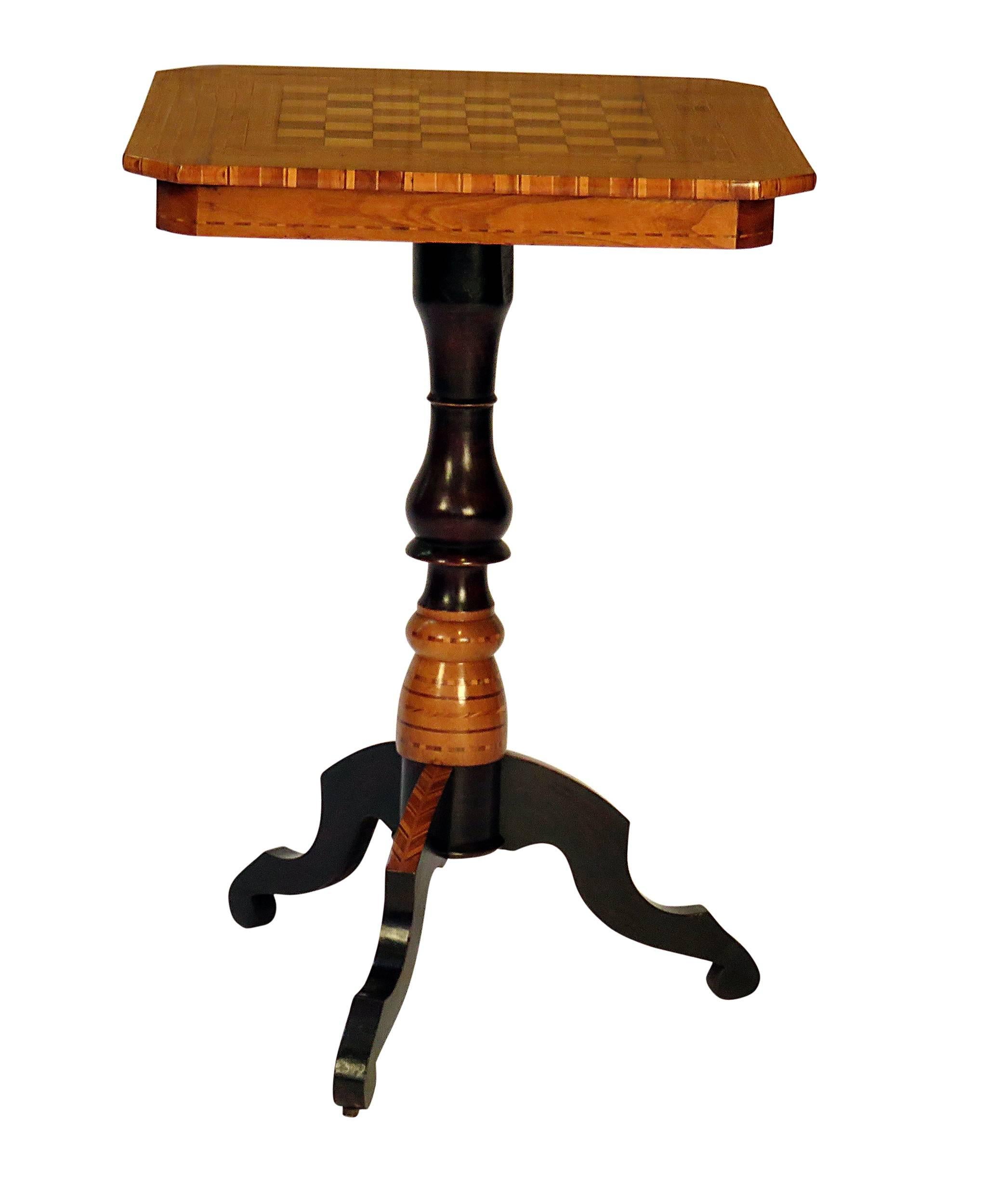 An inlaid Italian pedestal game table inlaid with a chess board. Mixed woods inlaid on poplar secondary woods. Probably made in or around Milan. A favorite souvenir of tourists in the late 19th century.
