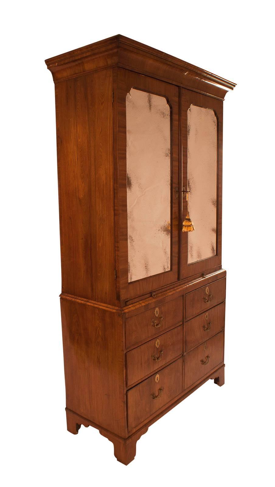 A good walnut linen press England circa 1730 mirrored doors over drawers with a brushing slide. Good color proportion and patina. From an old East Coast collection. Original mirror plates re-silvered. Useful and beautiful.