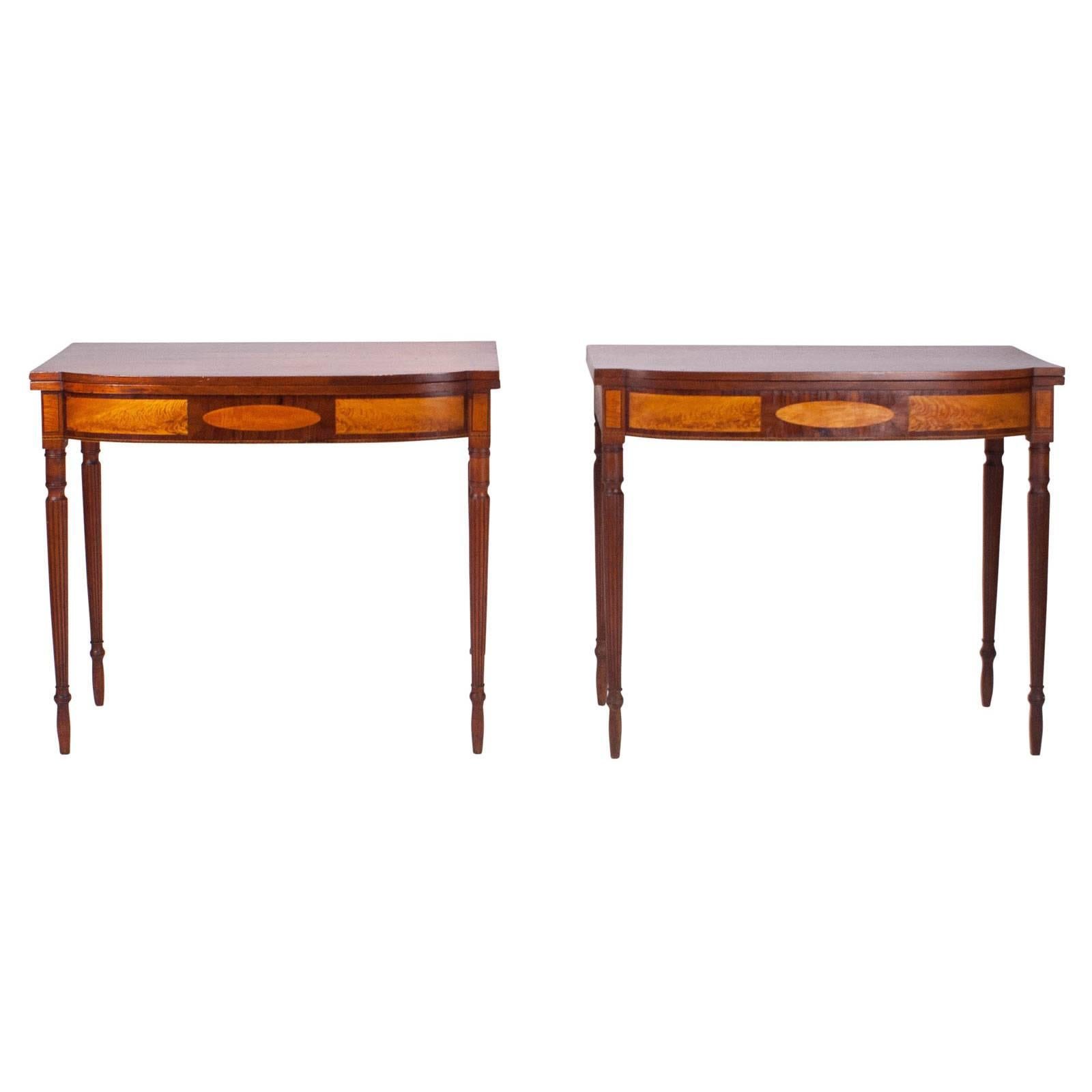 A pair of American Federal inlaid games tables on reeded turned tapered legs, New England region circa 1810. The tables are mahogany inlaid with satinwood, rosewood and checked stringing. One top refinished.