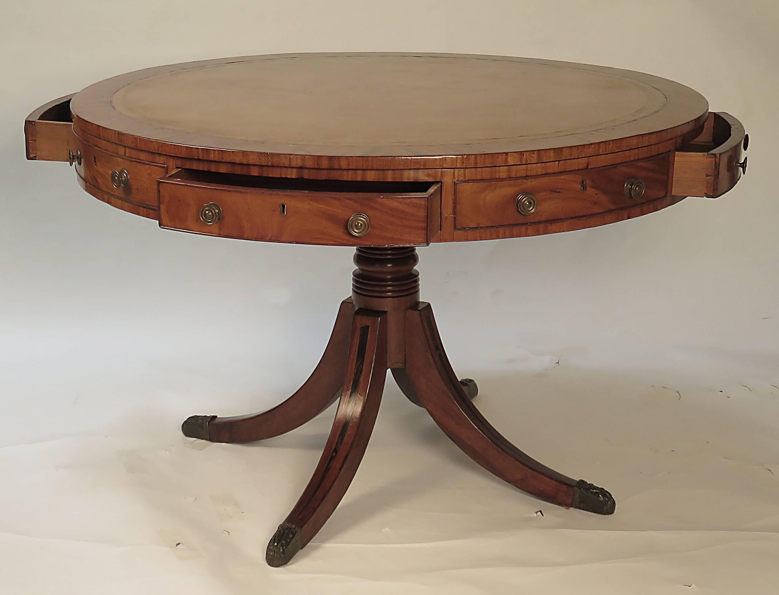 A handsome Classic and large English center, library, rent or drum table made about 1860 with inset leather top and four rosewood inlaid saber legs. This design was popular throughout the 19th century. It is first made late in the Georgian period.