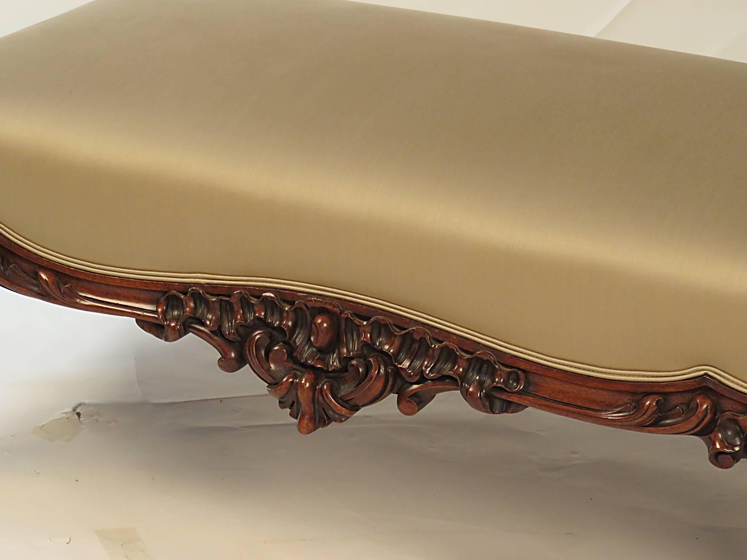 An unusually large Victorian English Rococo Revival ottoman made circa 1870. Exceptional carved details with rich Rococo flourishes. The color is a warm rich walnut tone and is possibly faded rosewood. The large size is a real rarity. Recently