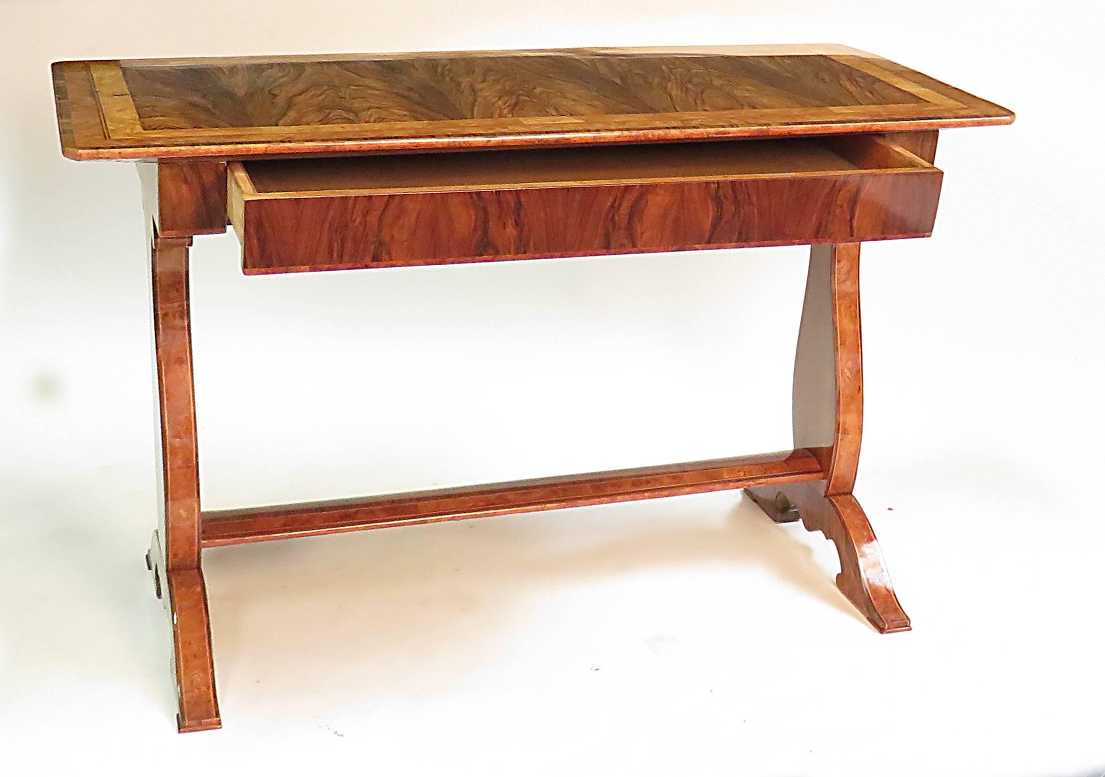 A useful and tailored Biedermeier inlaid writing table made in Austria, circa 1830. Frieze opens on one side as a long single drawer. Inlaid lyre shaped supports are joined by an elegantly shaped stretcher. Finished on all four sides so that this