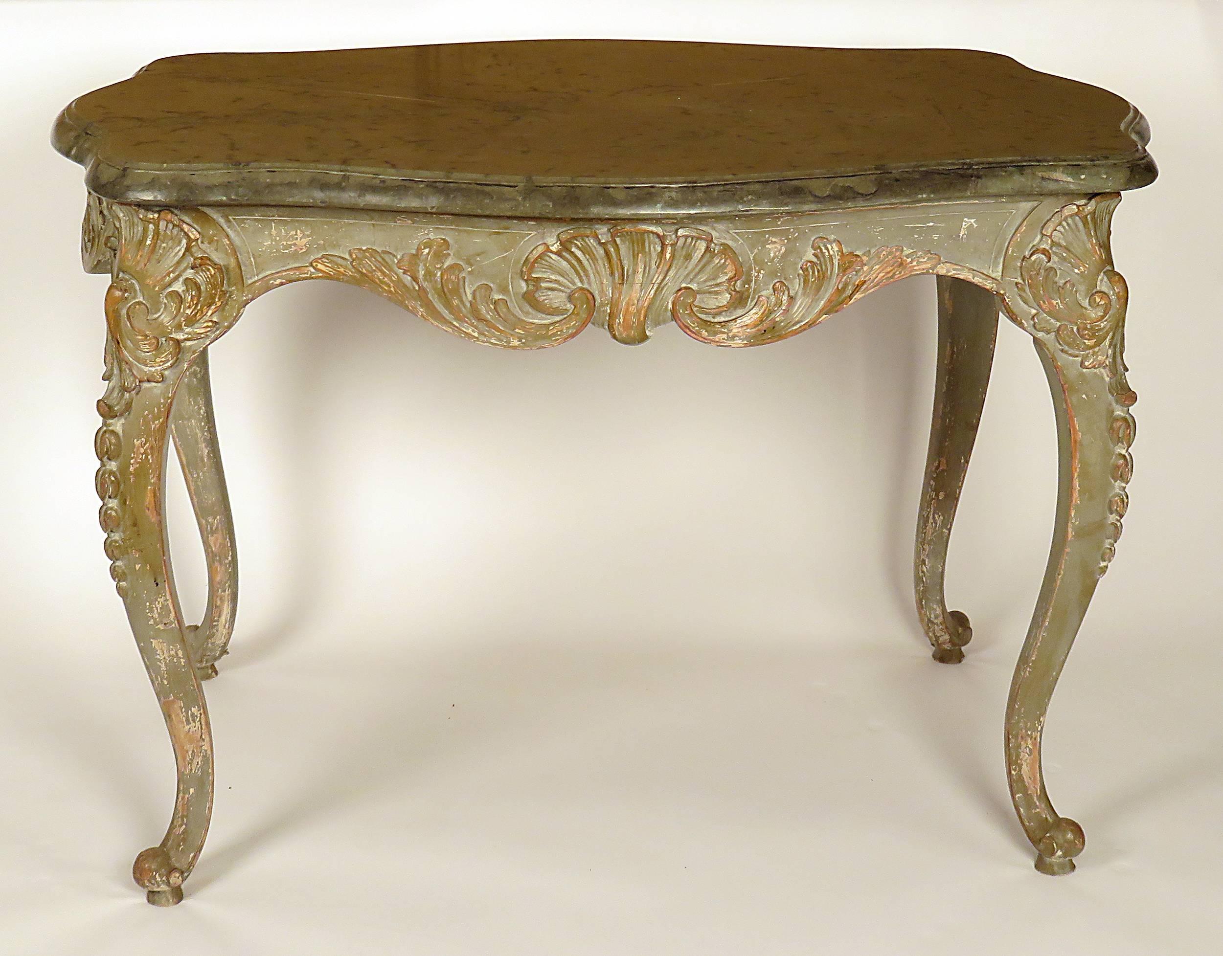 A nice Swedish Rococo table with original fossil marble top. Made to stand away from wall with carvings on four sides. Good older painted finish. With original marble.