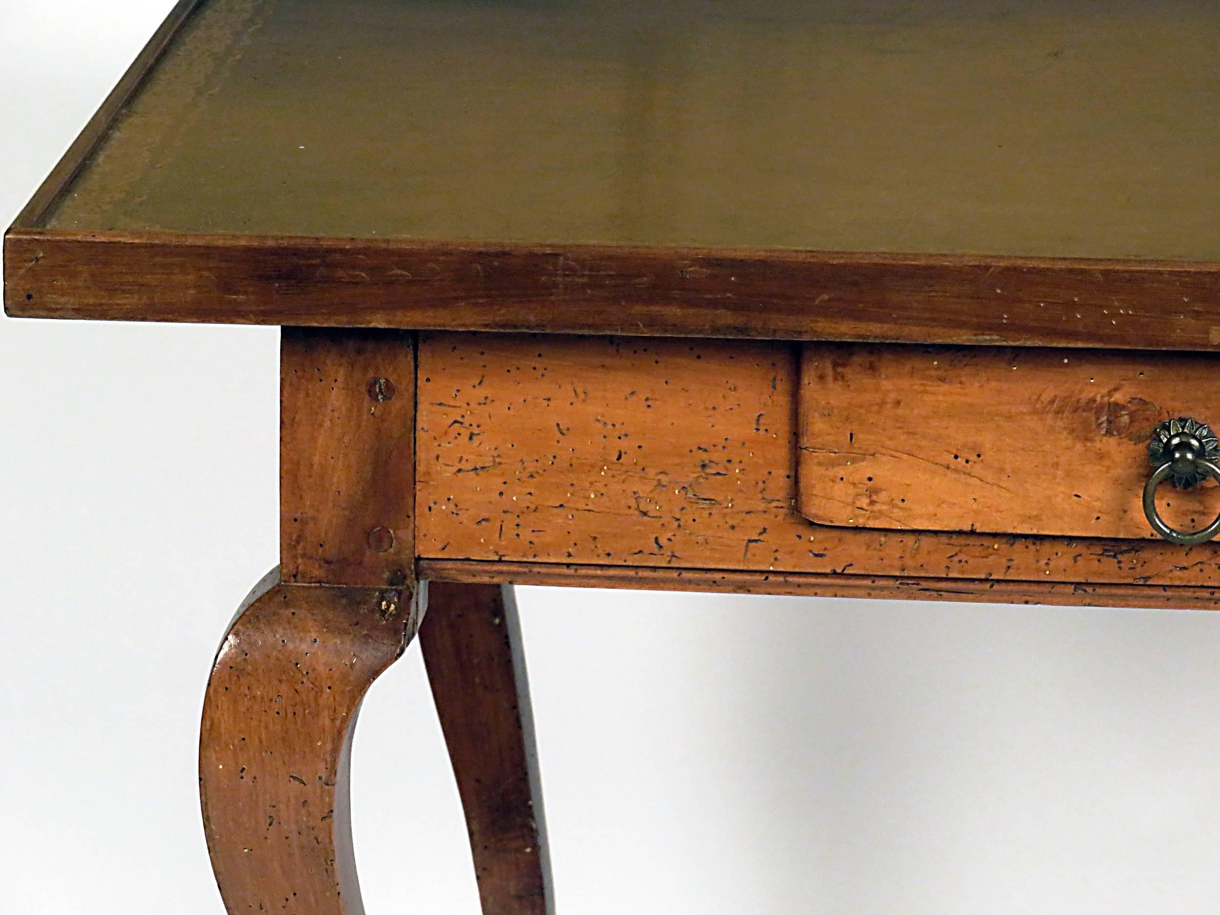 Italian leather topped walnut writing table with drawer, circa 1870. Standing on well carved cabriole legs with hoof feet. Nicely tooled and worn caramel leather top.