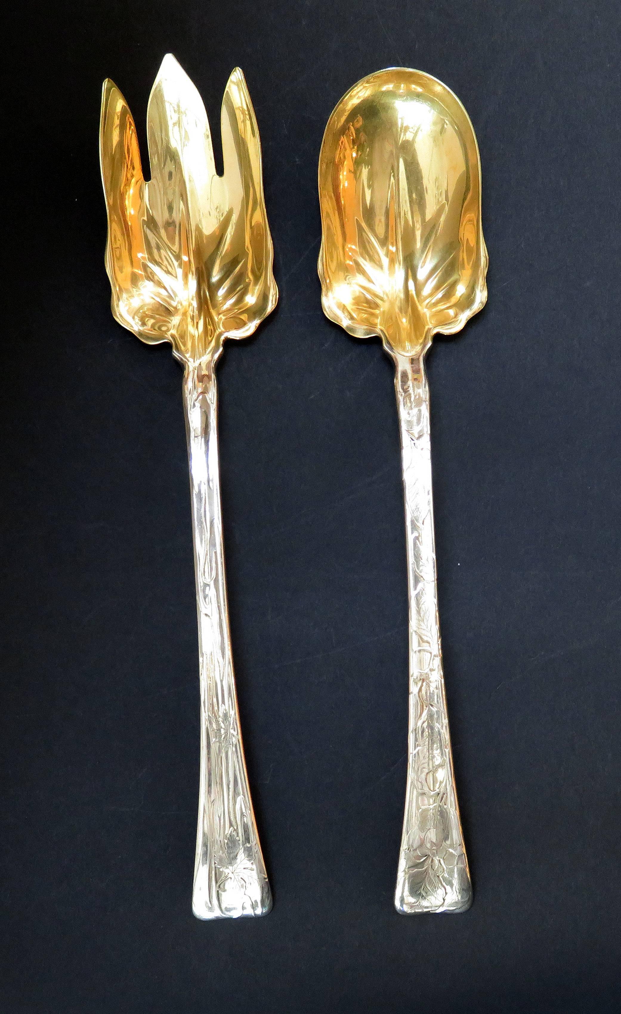 A Tiffany and Company lap over edge acid etched salad fork and spoon. Both the fork and the spoon have a gilt bowl. The fork is etched with maple leaves and the spoon is etched with leaves. The is a monogram on each piece of a 