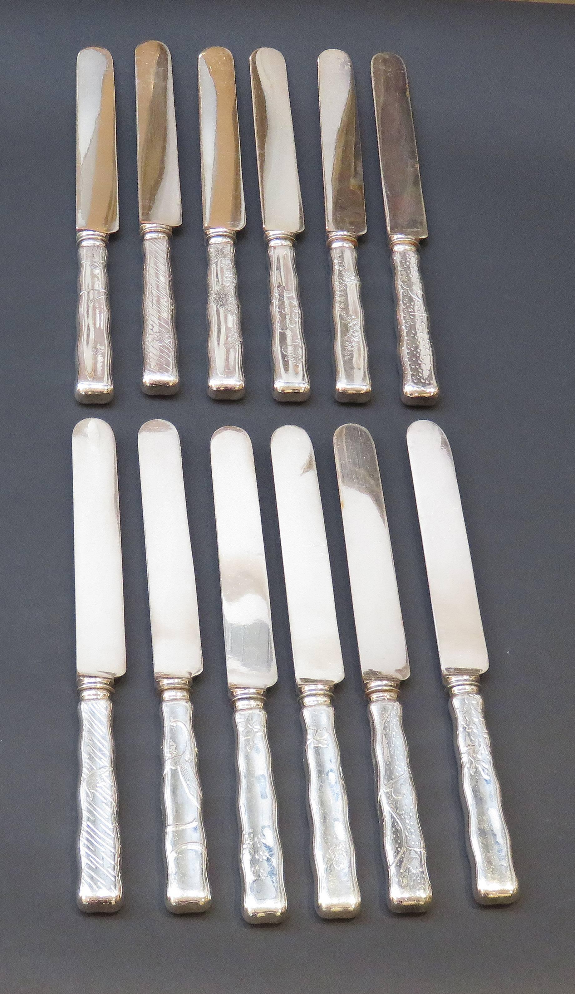 A set of 12 Tiffany & Company lap over edge acid etched hollow handled dinner knives. Each handle is etched with different sea life, fruit, plants and flowers. The blades of these knives are marked Tiffany & Co New York. The handles are marked