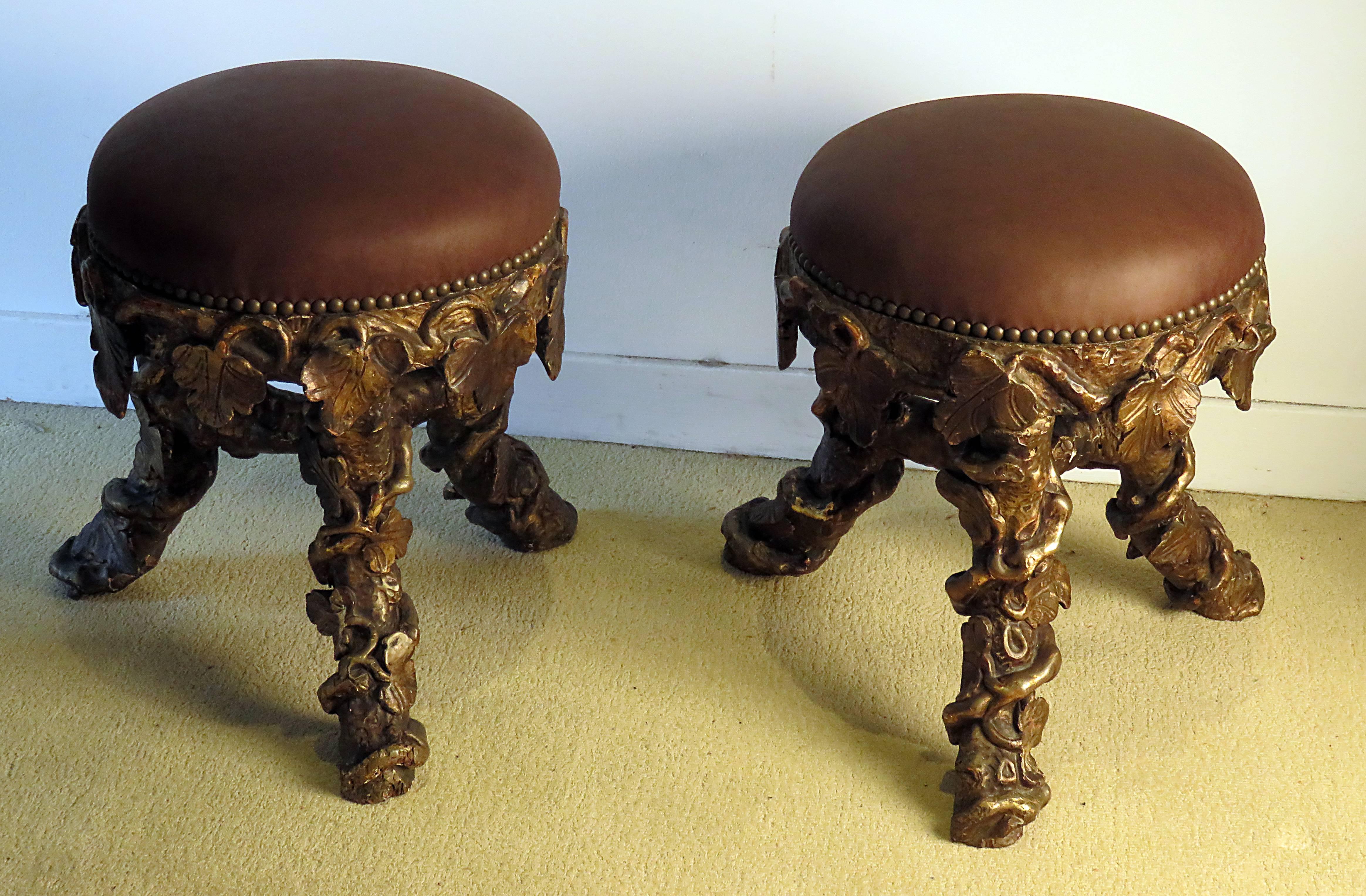 A very rare pair of Italian carved and giltwood stools in the grotto or fantasy furniture style. This pair is carved to imitate vines and branches. Recently upholstered in leather with brass nailhead trim. Pieces like these where made first in the