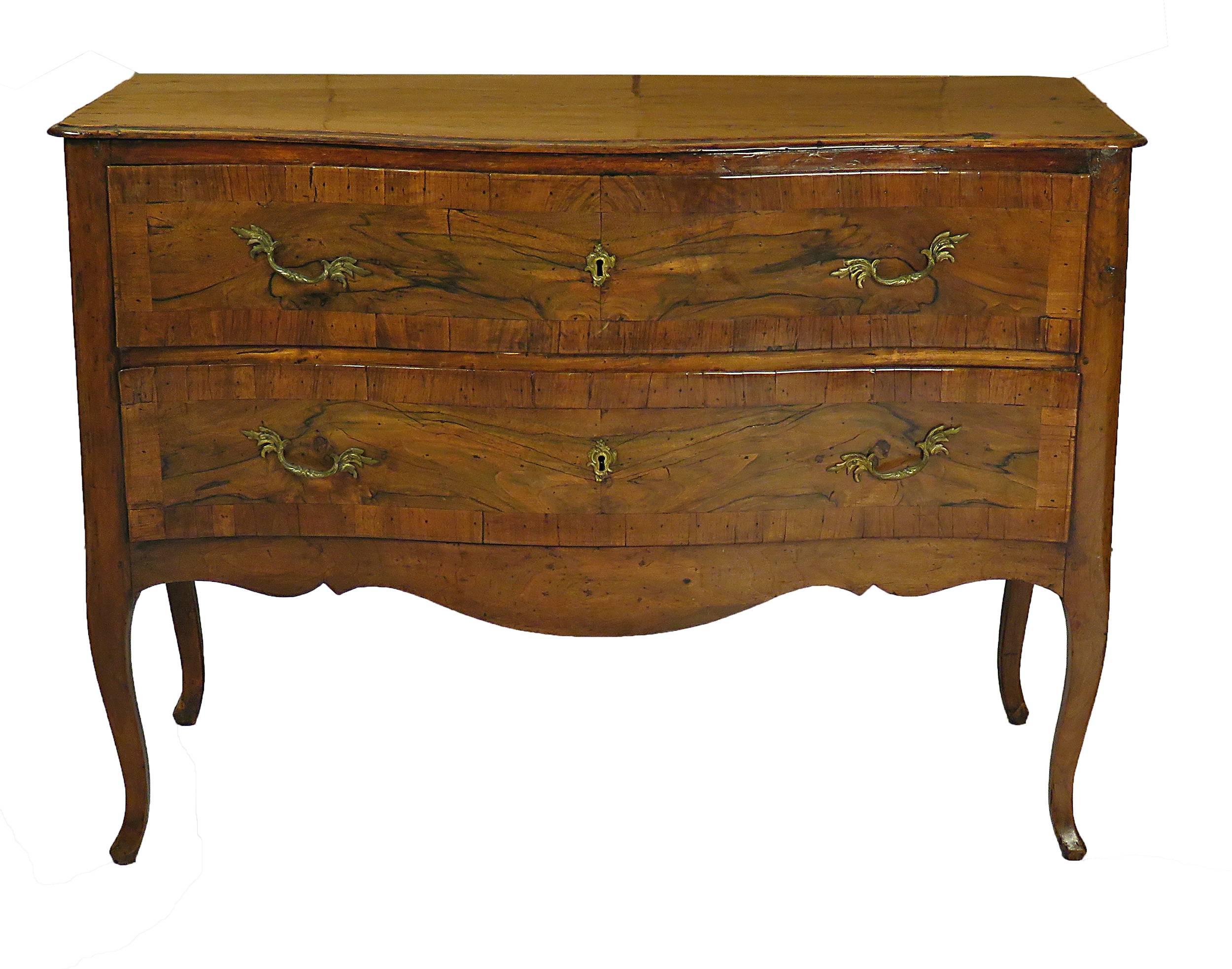 An early 19th century Italian two-drawer serpentine walnut commode, circa 1800. Nice mellow color with a good old surface. Particularly nicely carved cabriole legs.