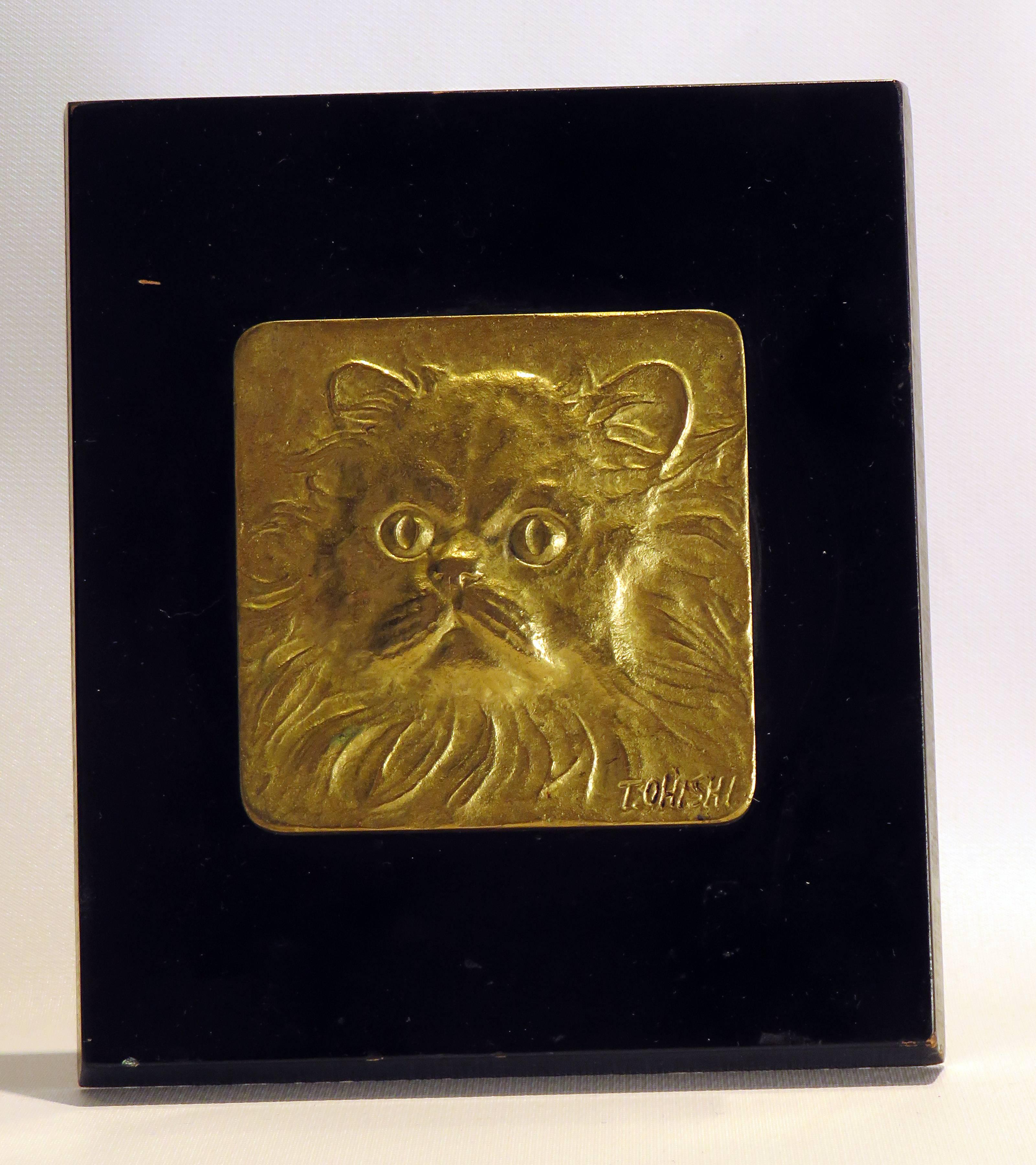 An interesting and elegant gilt bronze casting of a cats face in relief. Probably vintage. We are unable to determine the correct signature. Obviously a trained artist, circa 1960.