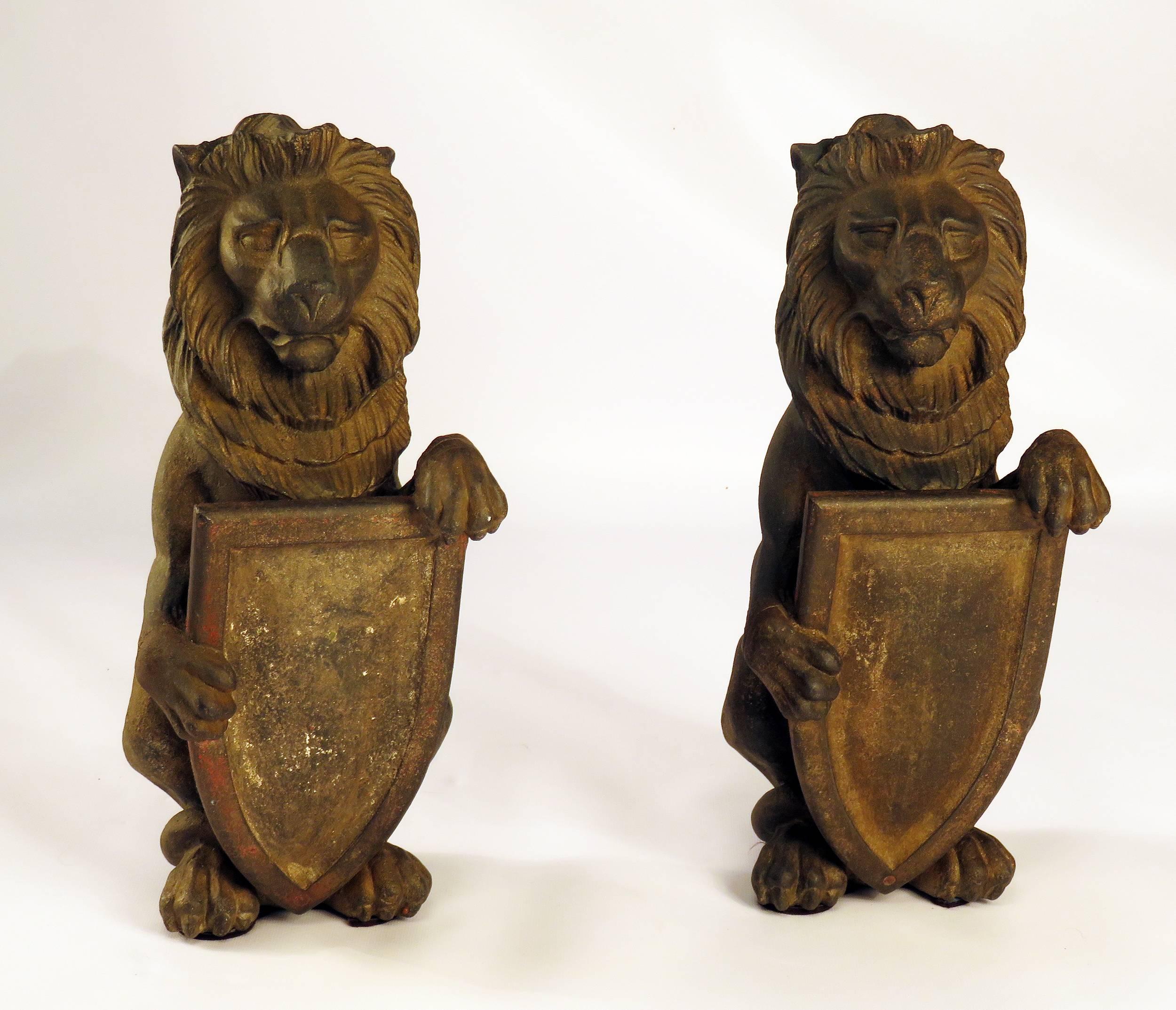 A pair of cast iron lions holding shields with traces of old paint. We believe these come from England and are Edwardian. Possibly gate post finials or andirons. Great decoration.