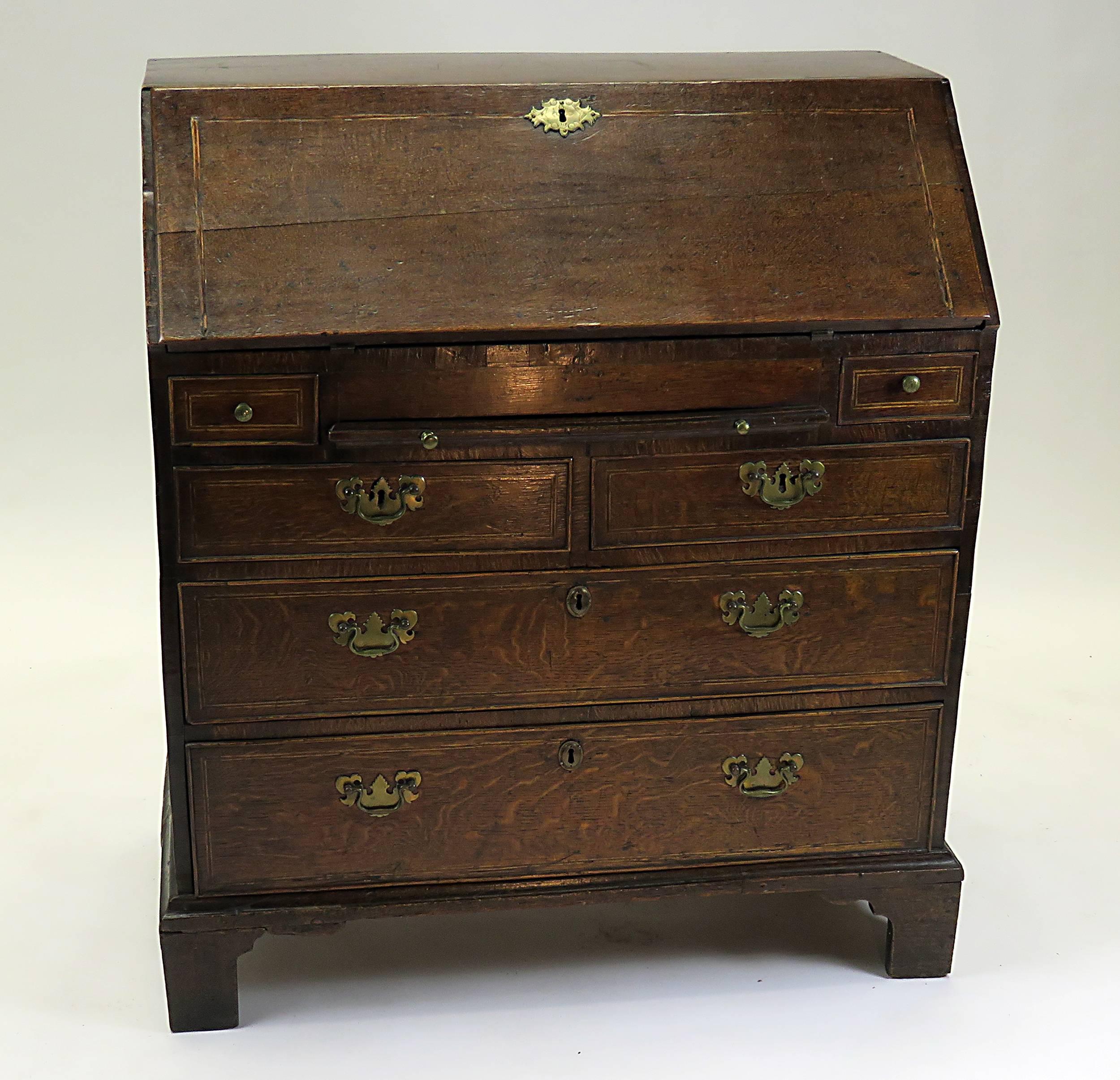 A handsome and rustic early Georgian oak slant front desk made in England during the first half of the 18th century. The interior is beautifully fitted with pigeon holes and stair stepped drawers. There is also a 