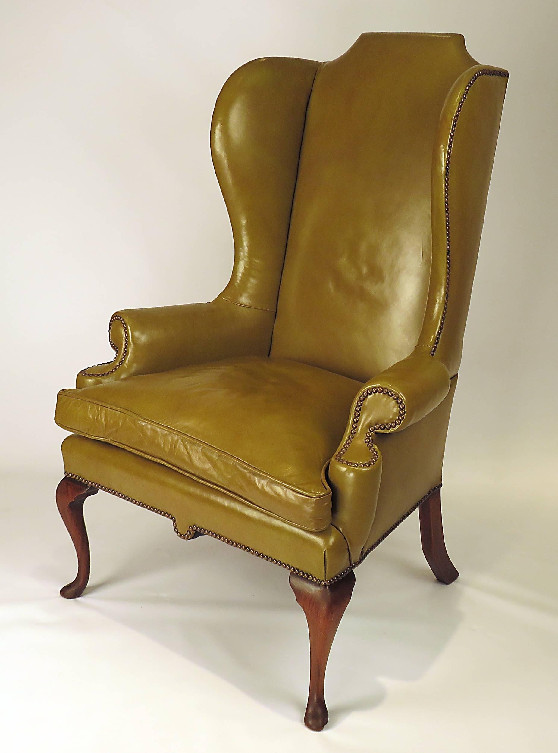 A well-proportioned English vintage olive green hide leather wing chair. Quality construction with nicely worn real leather. Classic design first seen, circa 1720. Comfortable and practical.