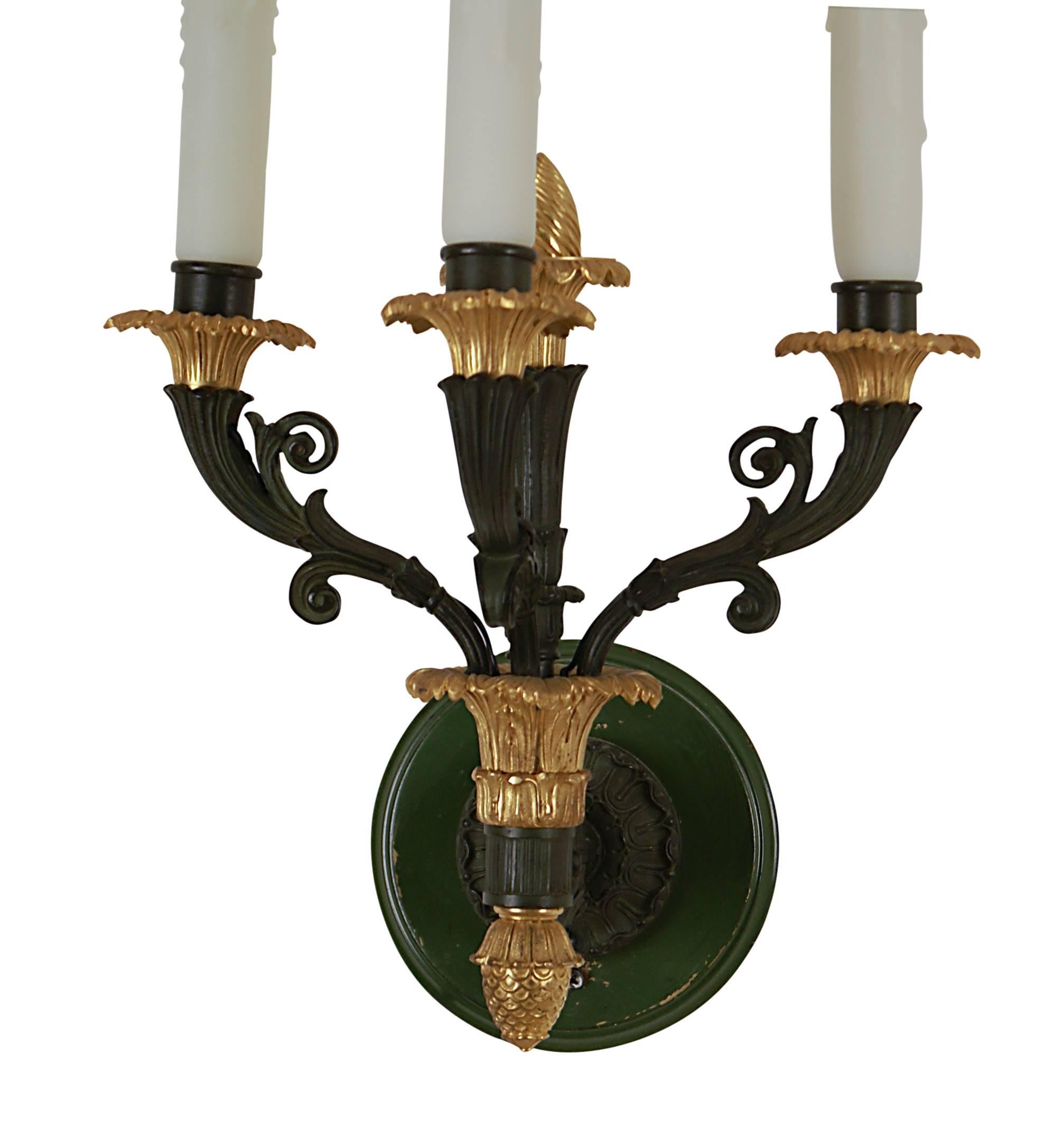High quality reproduction of a French Empire pair of three light sconces in bronze and gilt bronze. We date these to about 1920 when they where made in France. Now wired for electricity with later dark green painted back plates.