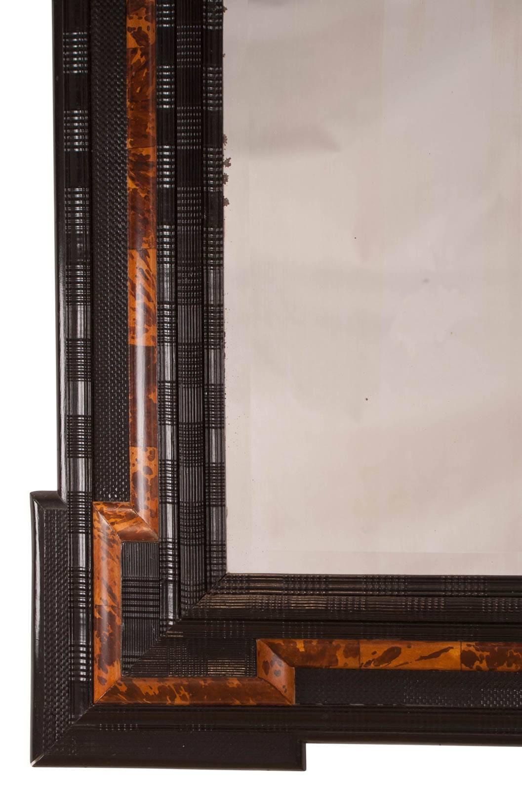 Flemish Baroque style mirror with faux tortoise painted in reserves. Nice hand-carved ebony moldings over a pine wood frame, circa 1880 mirror is very nice. The reflections of the studio background are largely what you are seeing.