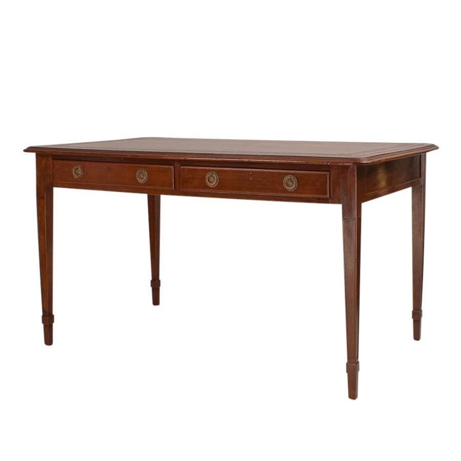 Early 20th century two-drawer mahogany writing table. Made during the Edwardian period after a design first made 120 years earlier. Good proportions, smaller size and what seems to be original tooled leather. Standing on four square tapered legs