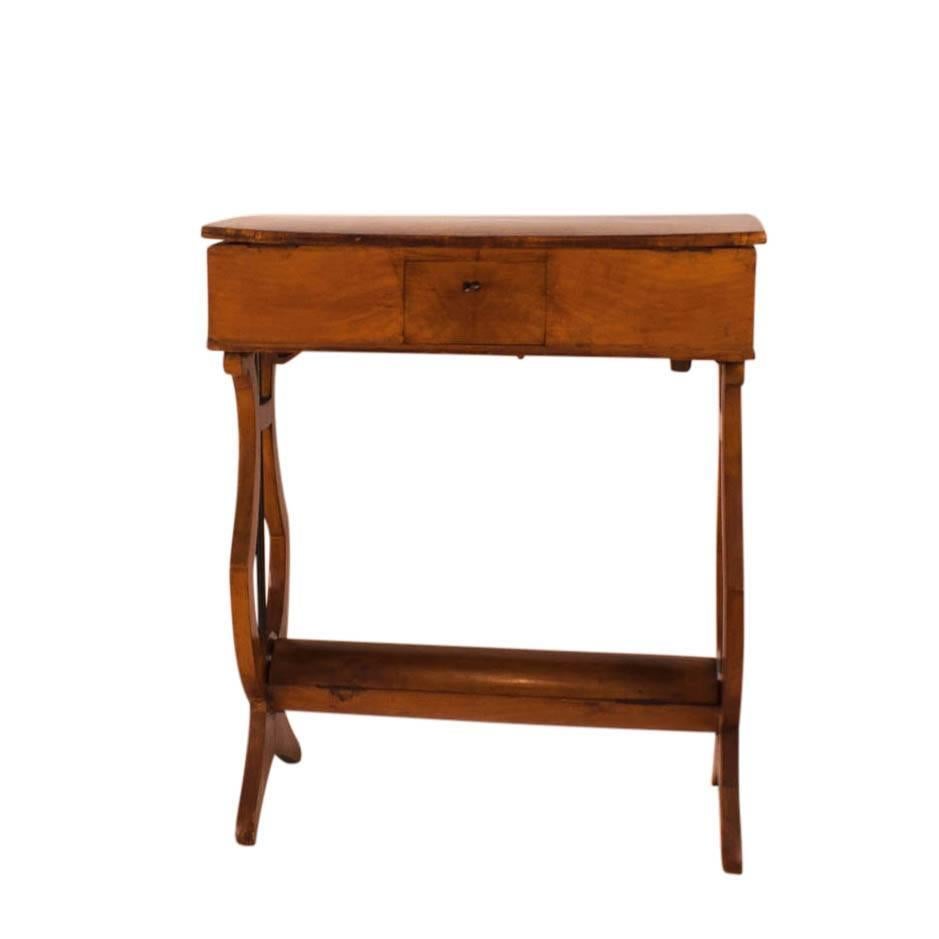 A well designed Italian work or sewing table made of cherry, circa 1830. The top fitted with various storage compartment and two opposing drawers. The oval stretcher folds open offering an unexpected hiding and storage. The lyre or harp supports are