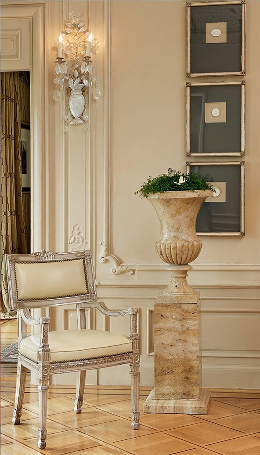 Pair of beautiful solid limestone classic form urns raised on plinthform bases with stepped bases. The figural quality of the stone is beautiful and the natural feeling of it's imperfections shows it"s patina and age. The urn are in three