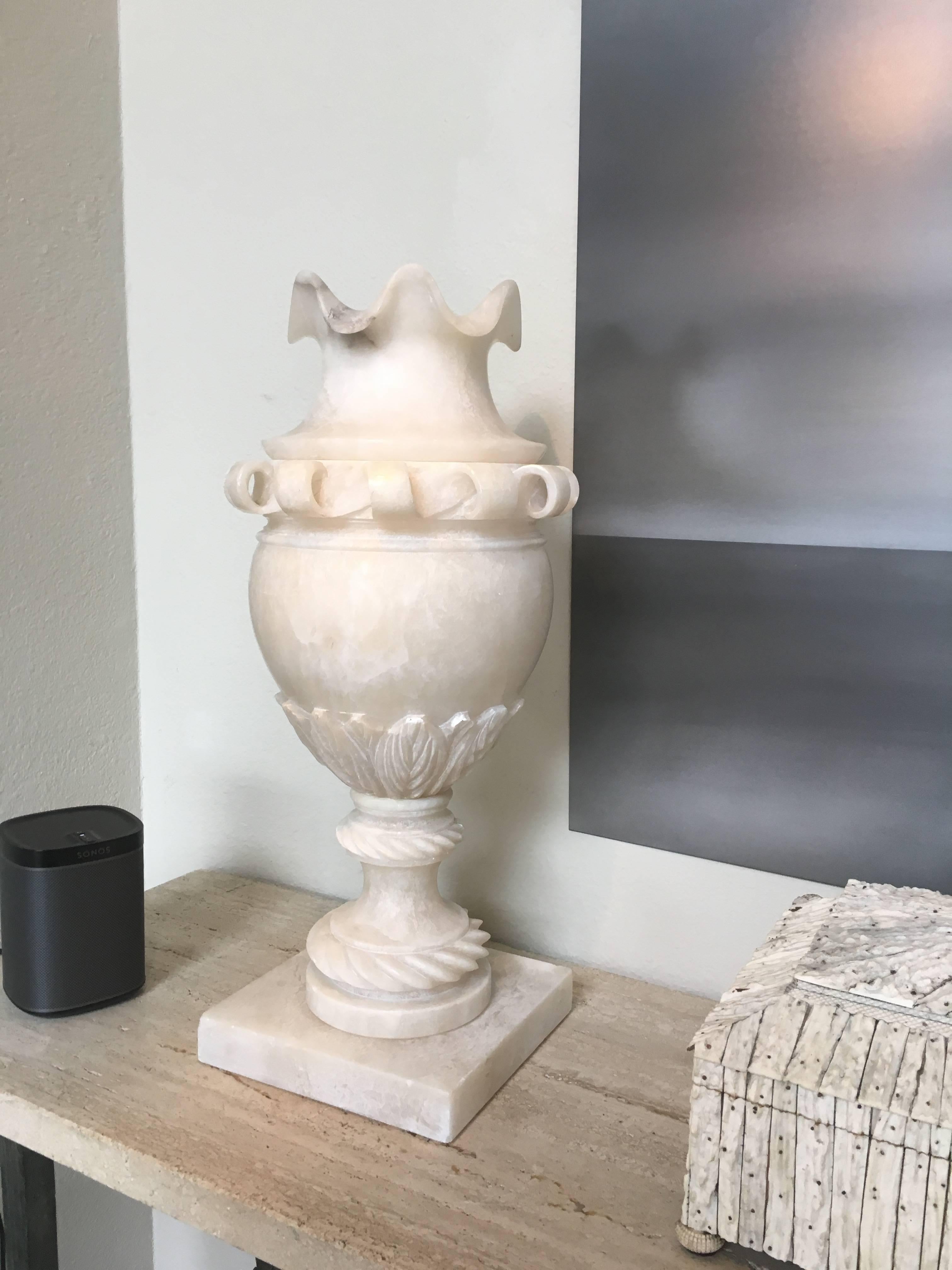 Turn of the century grand scale pure white marble classic form urn. This urn has scrolling ribbons around the top below a pie crust opening. The base features a twisted rope detailing with carved acanthus leaves, the whole raised on a square