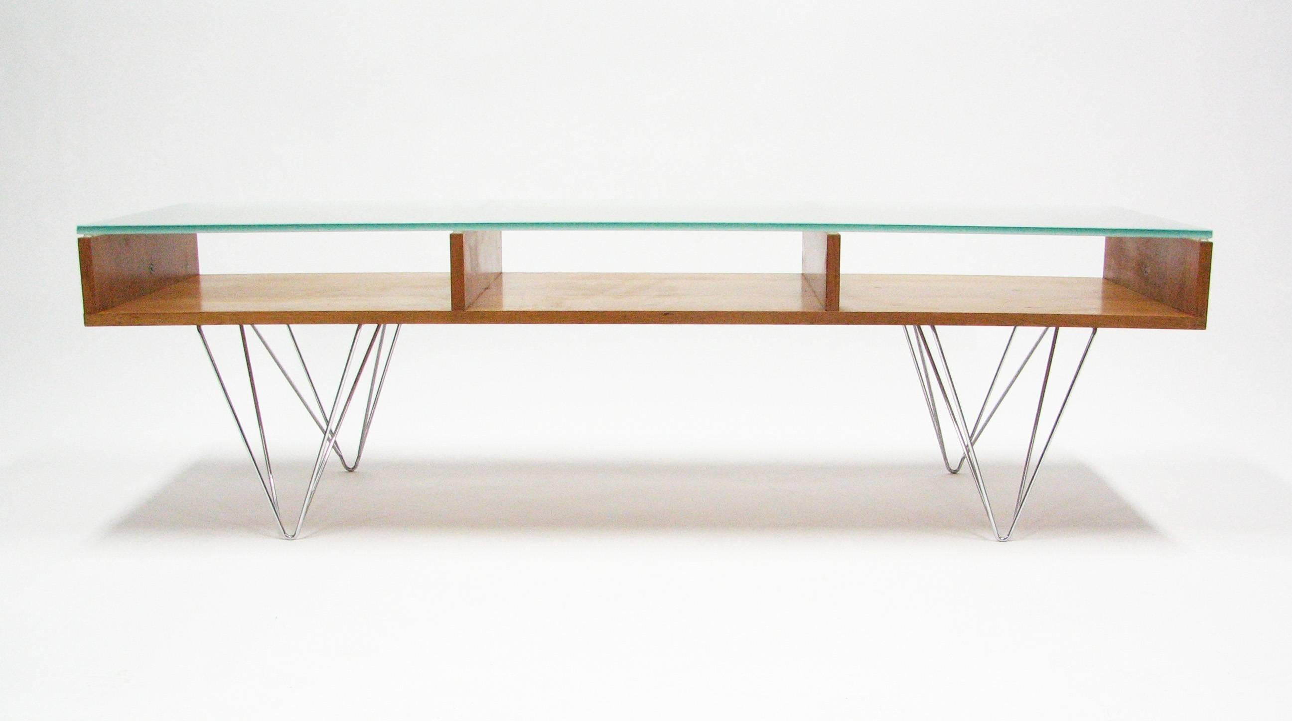 A cherrywood cocktail table with a frosted glass top over three open compartments on chromed, double hairpin legs. Origination: Postmodern architectural, interior design and furniture firm Bobo Modern Living, Boulder, Colorado (featured on 'Oprah'