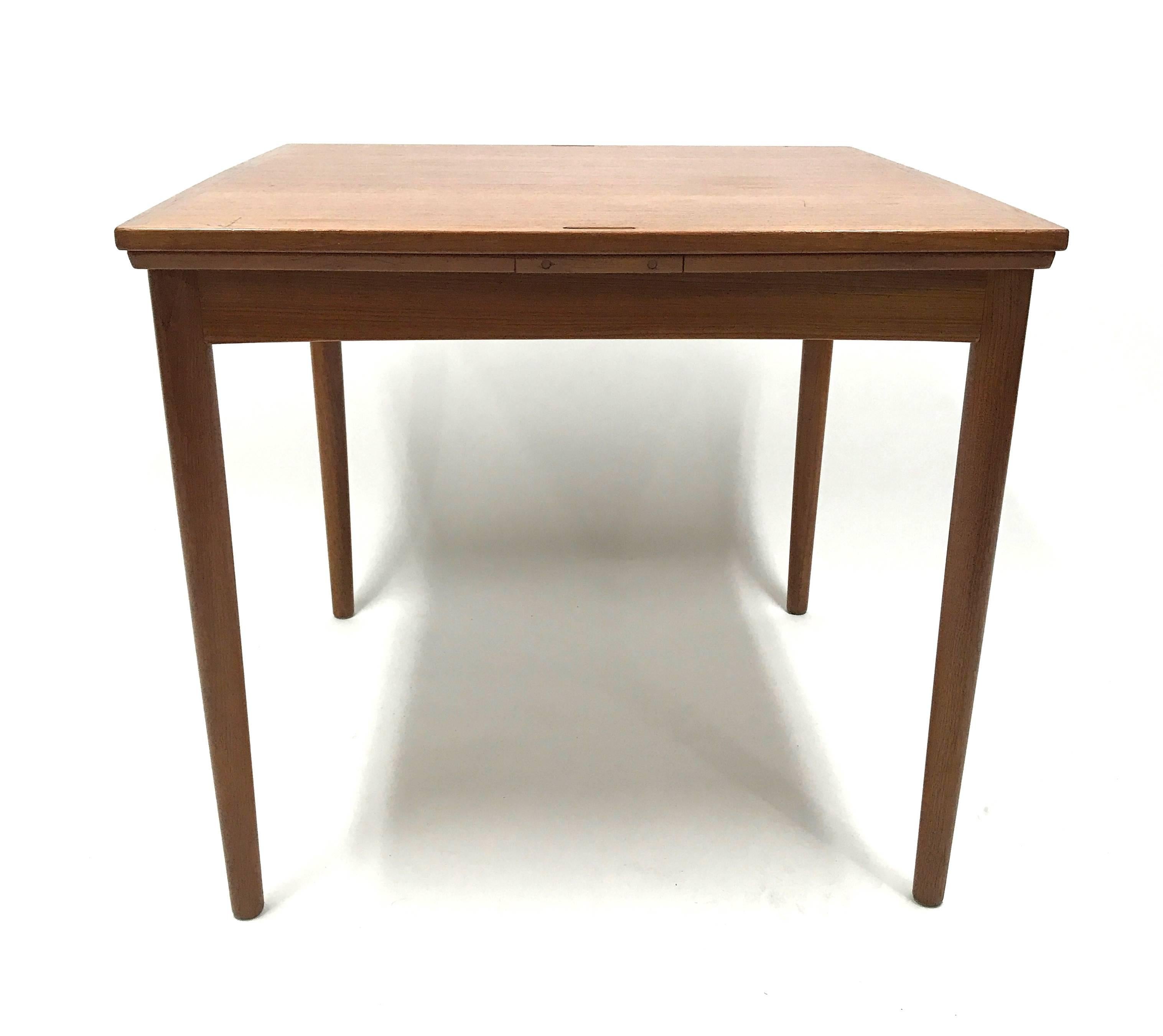 This 1960s reversible-top Danish teak table in the manner of Poul Hundevad with pull-out extendable leaves is perfect for a game room, kitchen or a versatile extra dining table for large gatherings. 

The reversible flip-top is teak on one side,