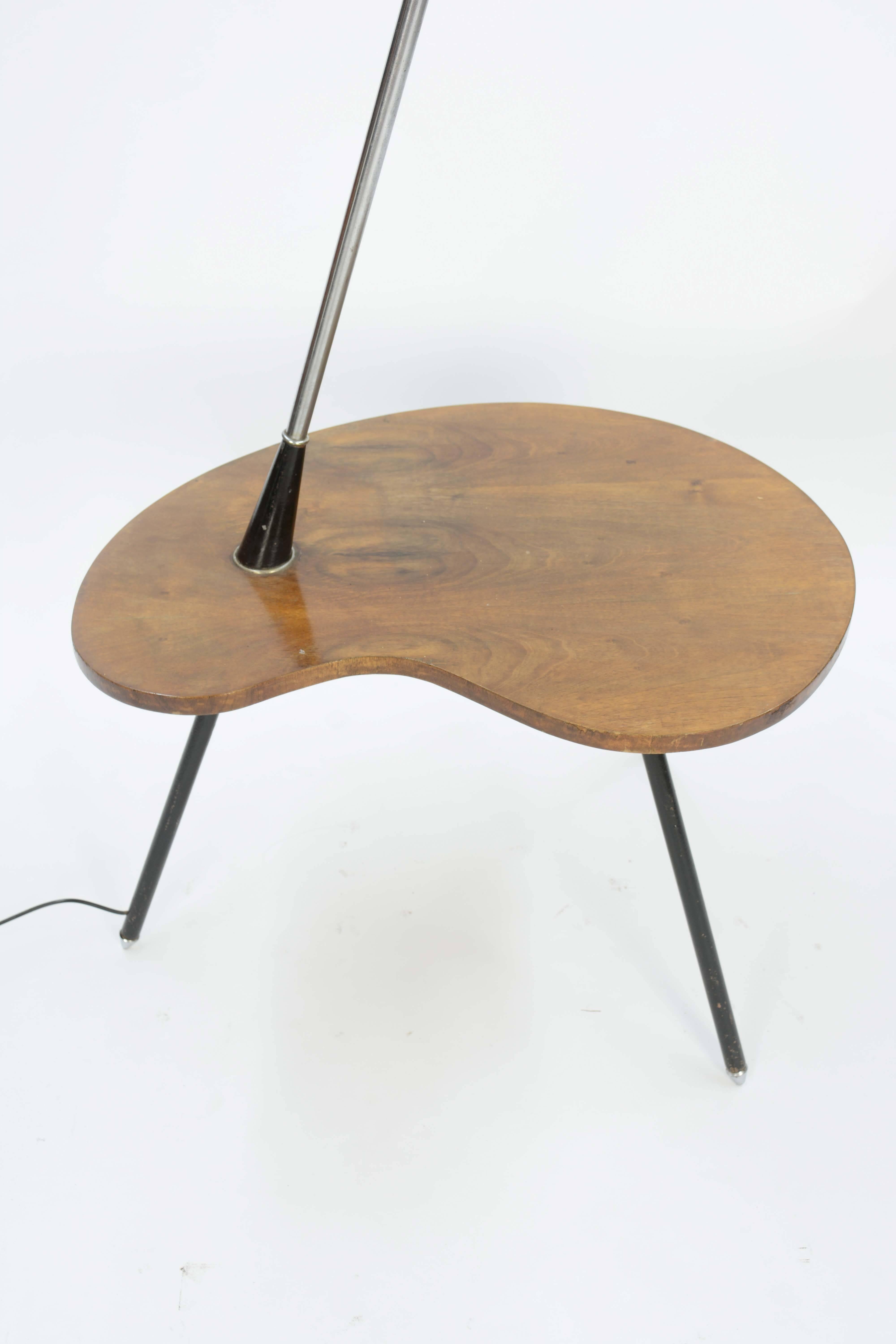 An atomic lamp table from Denmark with walnut table. An imported Danish floor lamp with a walnut biomorphic table top and a through angled leg to an amber globe. The tabletop is shaped like a painter's palette, 6