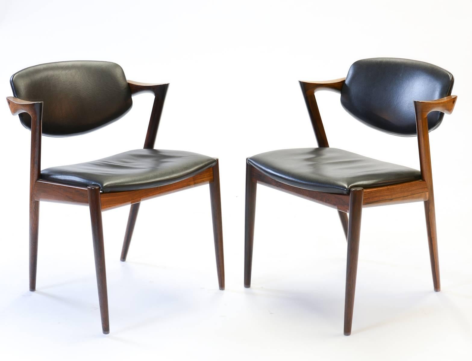 An iconic Danish design in rosewood with black saddle leather backs and seats by legendary designer Kai Kristiansen. The elegant frame lines grandly serve both timeless beauty and highly serviceable comfort. Set of six. Measures: Arm height 26".