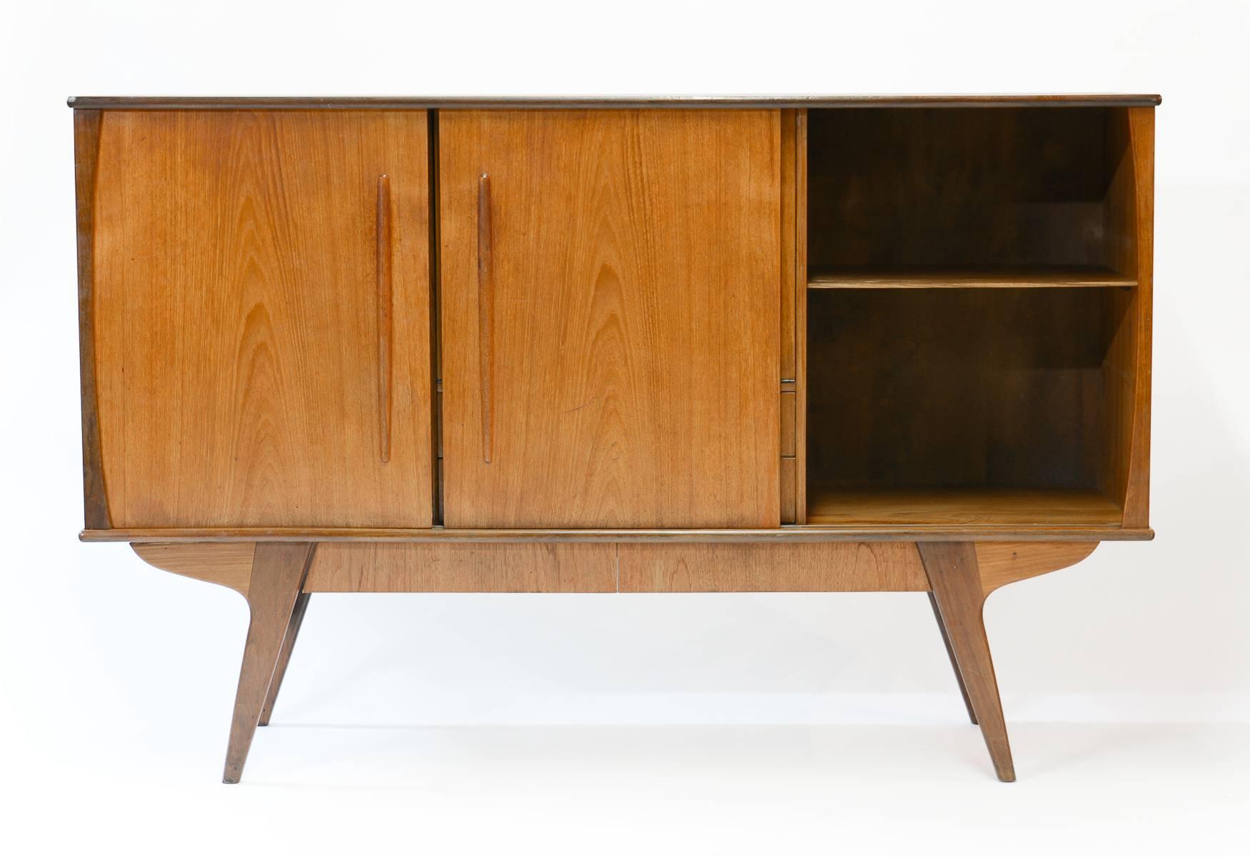 An elegant Danish teak sideboard with angled legs, hidden bottom drawers and drop-door bar perfect for entertaining. Beautifully streamlined and refined in design for a fabulous mid-century look in any home or office. This sideboard features left