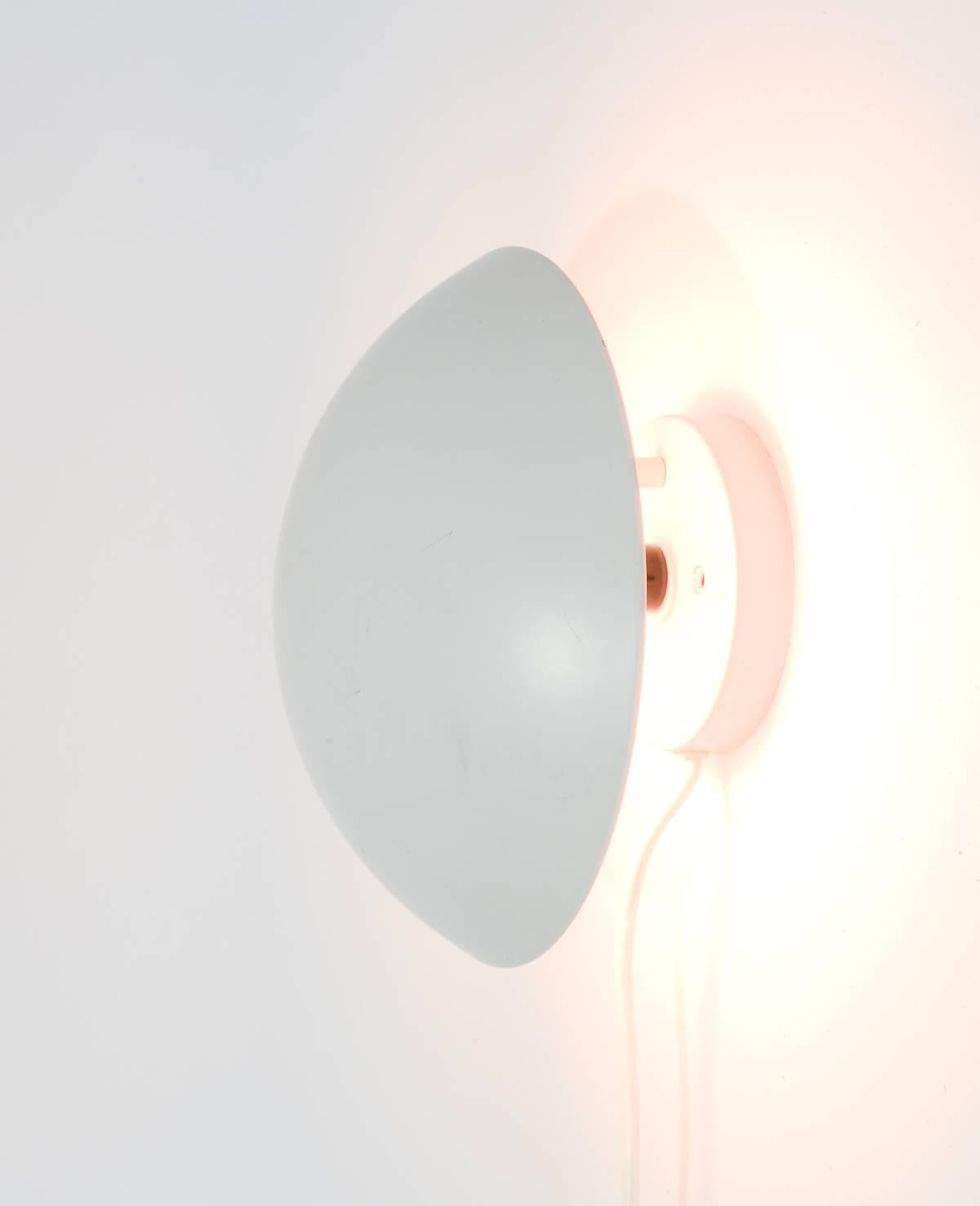 A pair of articulating P-Hat wall sconces by Poul Henningsen for Louis Poulsen. In arctic mat white with pink reflector interiors. A sophisticated wall lighting solution for home or office. Shade tilts from 5.5