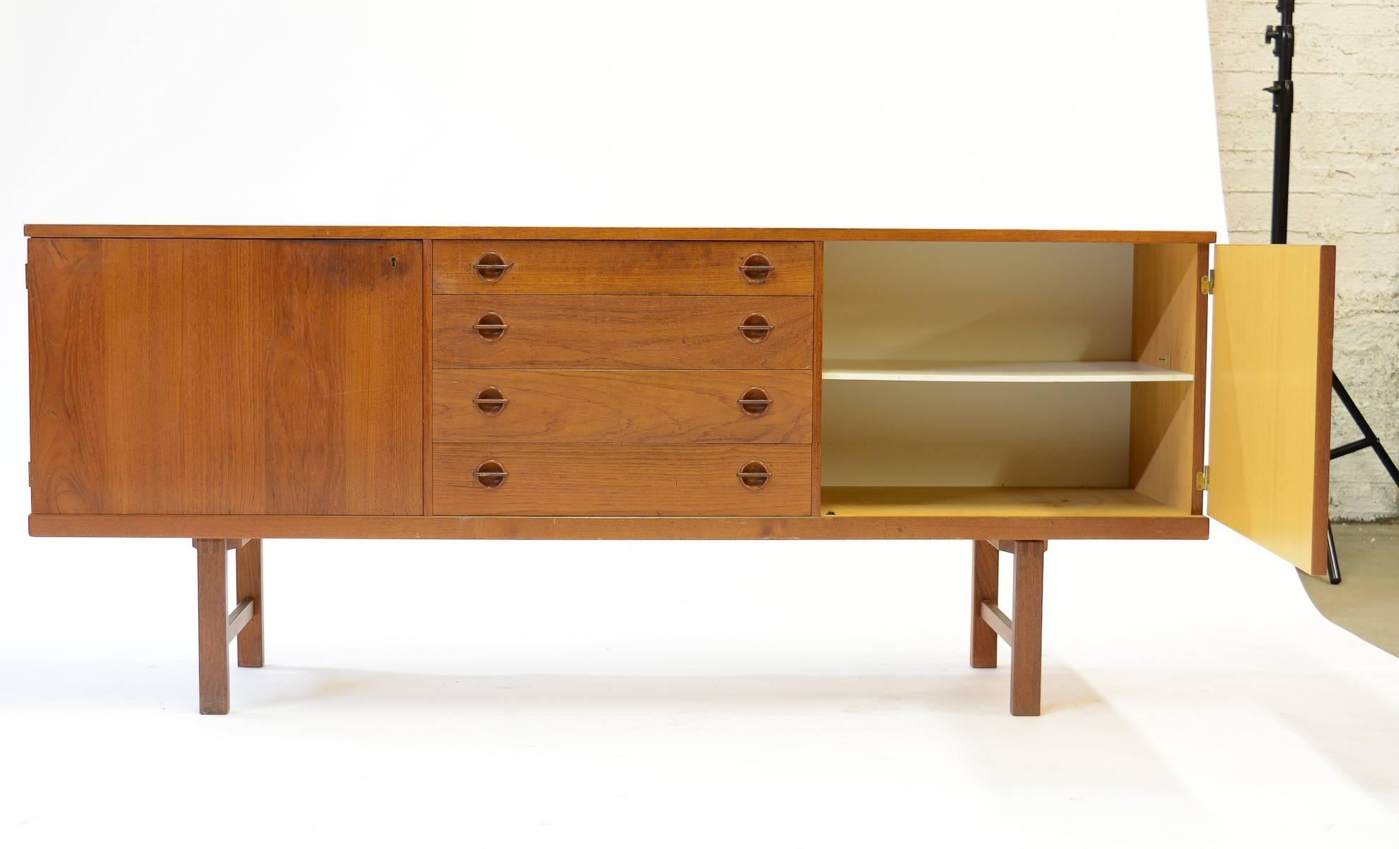 An exceptional Danish teak credenza with elegant circular drawer pulls on four stacked center drawers and an adjustable shelf in each of the left and right compartments.

