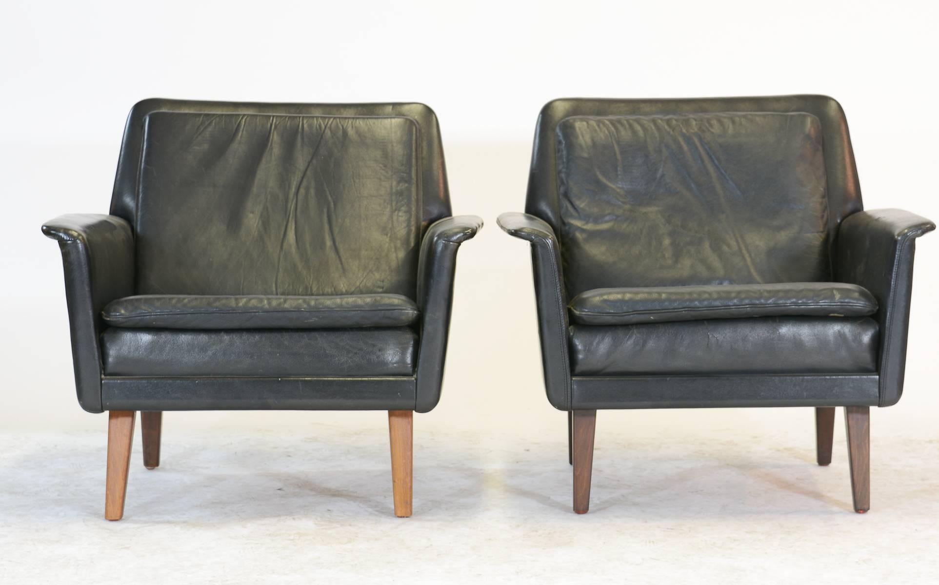 A pair of Lyon series club chairs by notable Swedish designer Alf Svensson for Fritz Hansen in black leather.  These rare editions, recently discovered in Scandinavia, are a subtly-styled Mid Century take on a classic design.  Original metal tag on