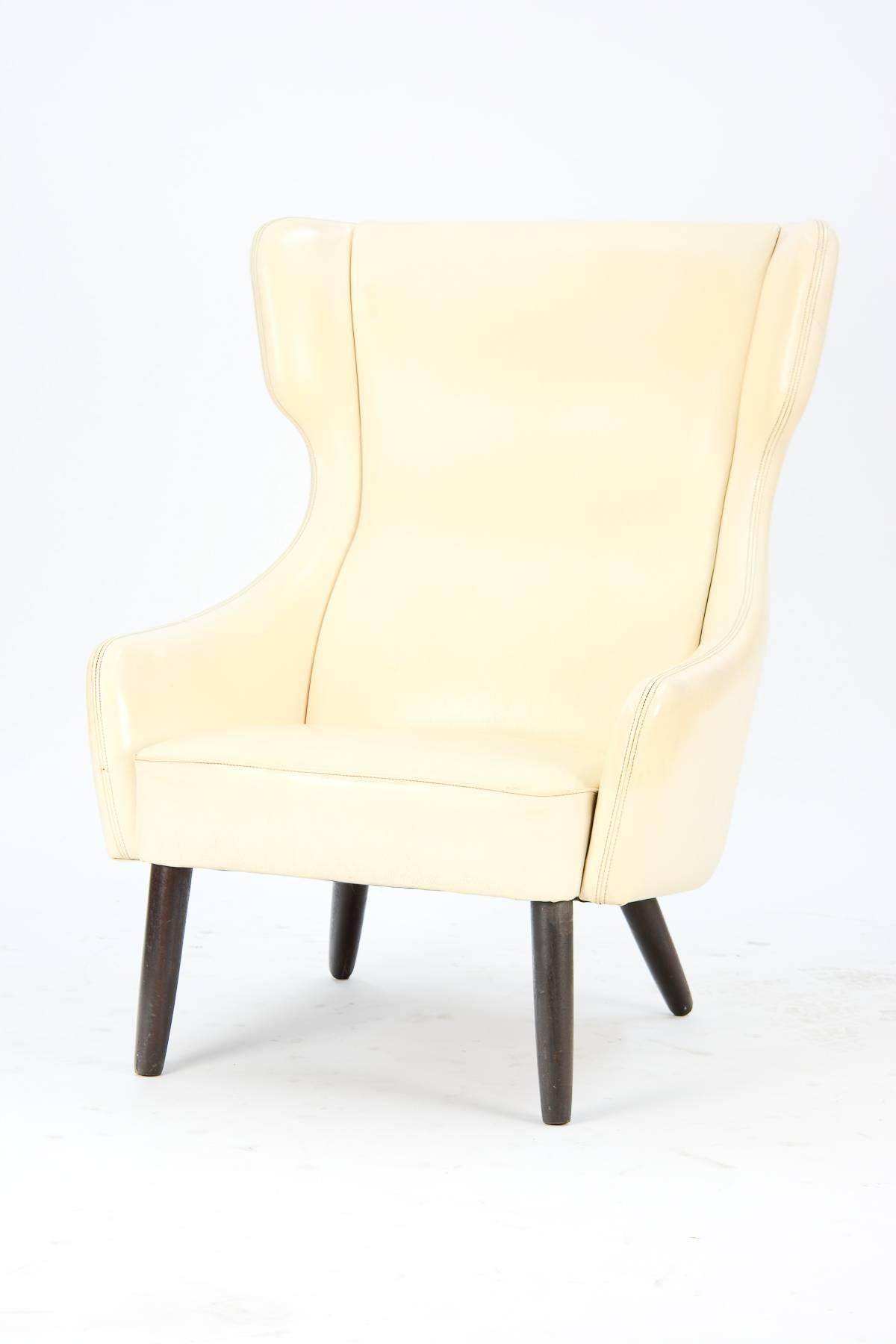 A distinctively-styled wingback armchair recently imported from Denmark. The wide seat and sophisticated design invite hours of comfortable reading or socializing.

In original cream leather. Arm height is 19.5 inches.