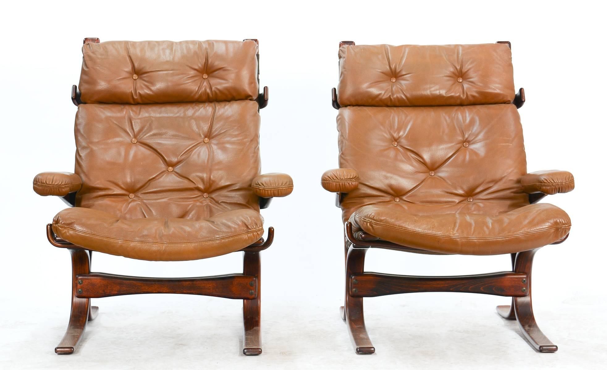 A pair of high-back sling club chairs after Ingmar Rellings with beautiful beech suspension frames and arms and cognac-colored leather upholstery on a canvas base.
 