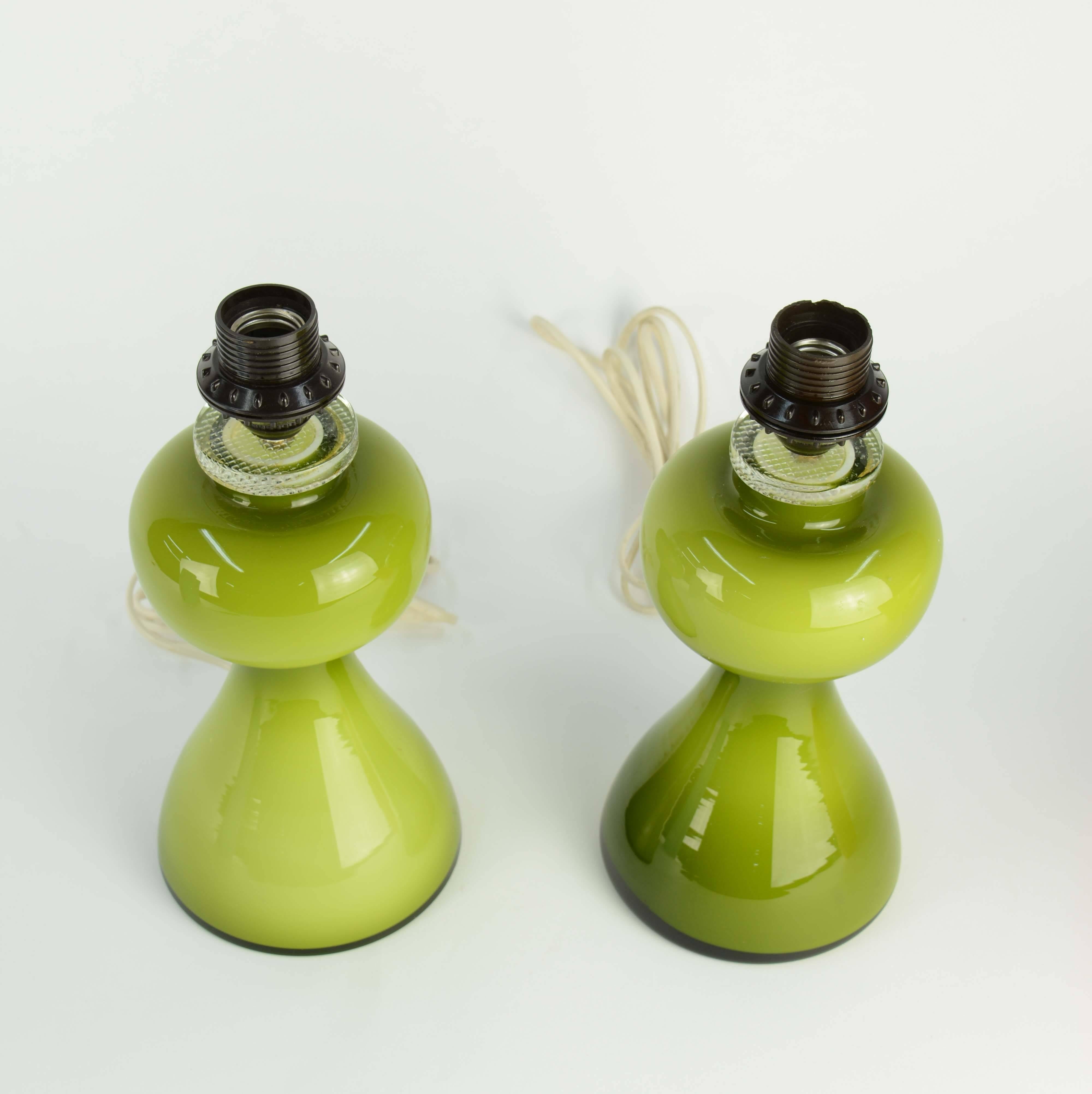 A handsome and striking pair of green glass lamps by Per-Olof Strom for Alsterfors. The lamps are crowned by clear glass collars. A wonderful example of refined Swedish glass work.