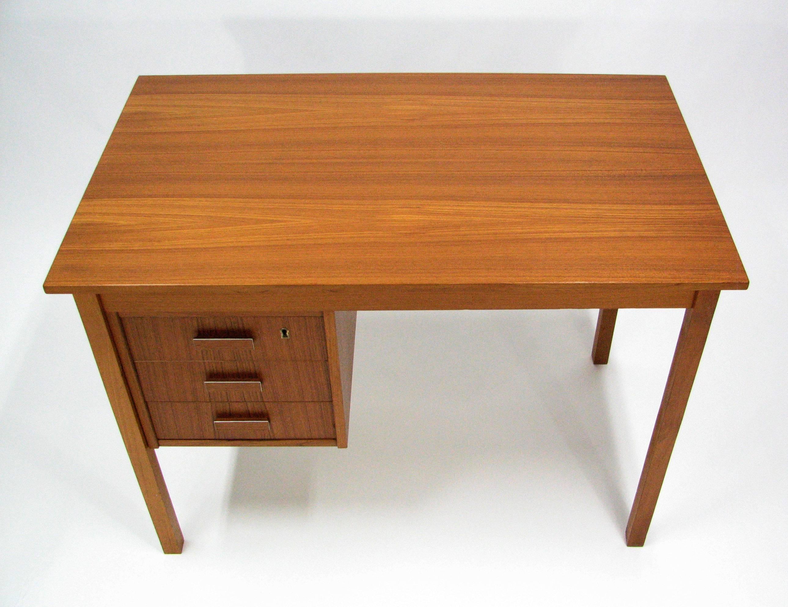A strikingly handsome midcentury teak writing desk by Ejsing Møbelfabrik A/S. 

Three locking drawers with teak and aluminium pulls and the original key. The richly-grained back of the drawer cabinet is stunning, and makes this a desk that can be