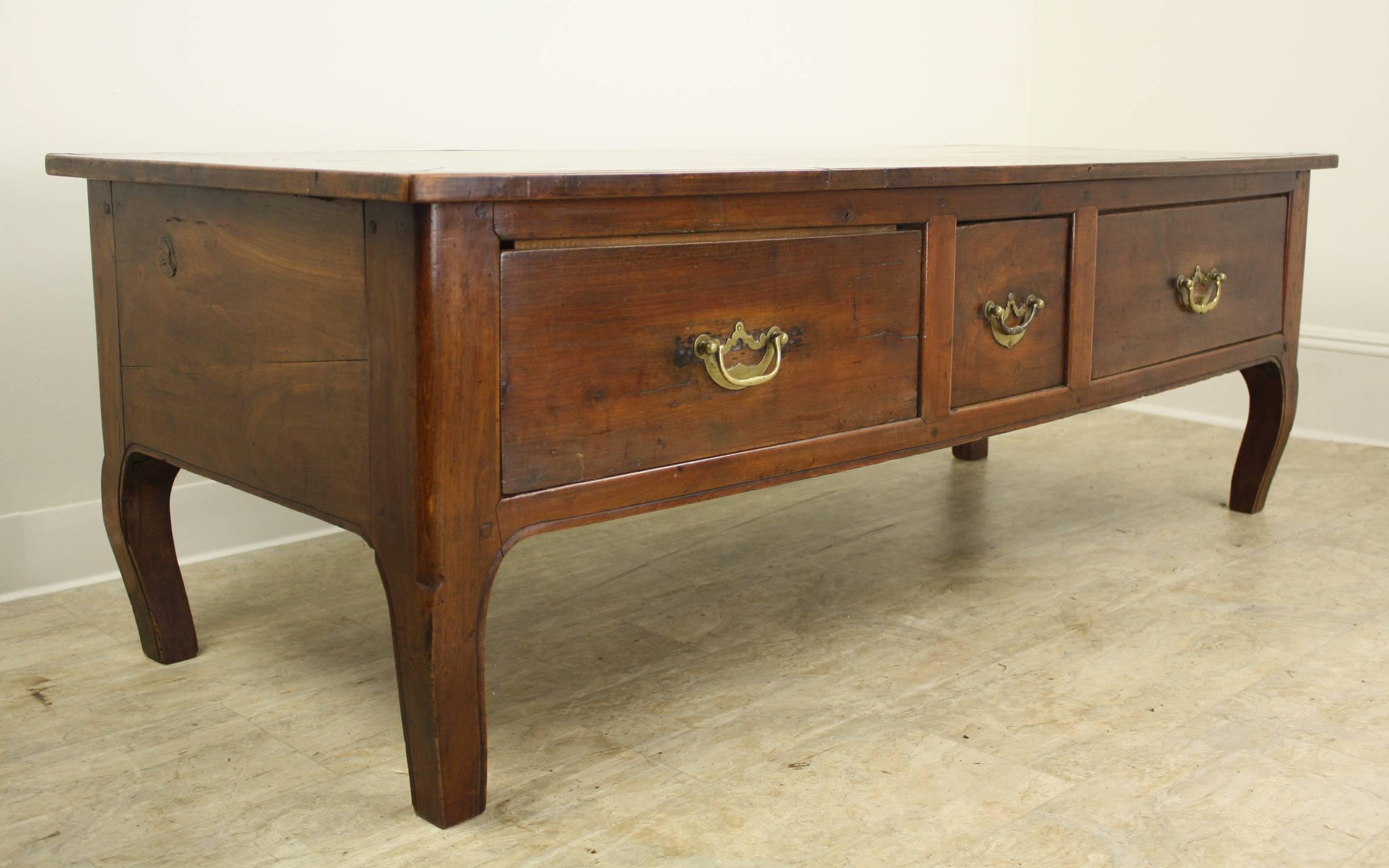 There is a lot to love about this graceful coffee table in warm cherry. The top has both Fine carpentry detail such as mitred corners and neat trim, with interesting old distress. The body of the piece boasts three deep roomy drawers with solid