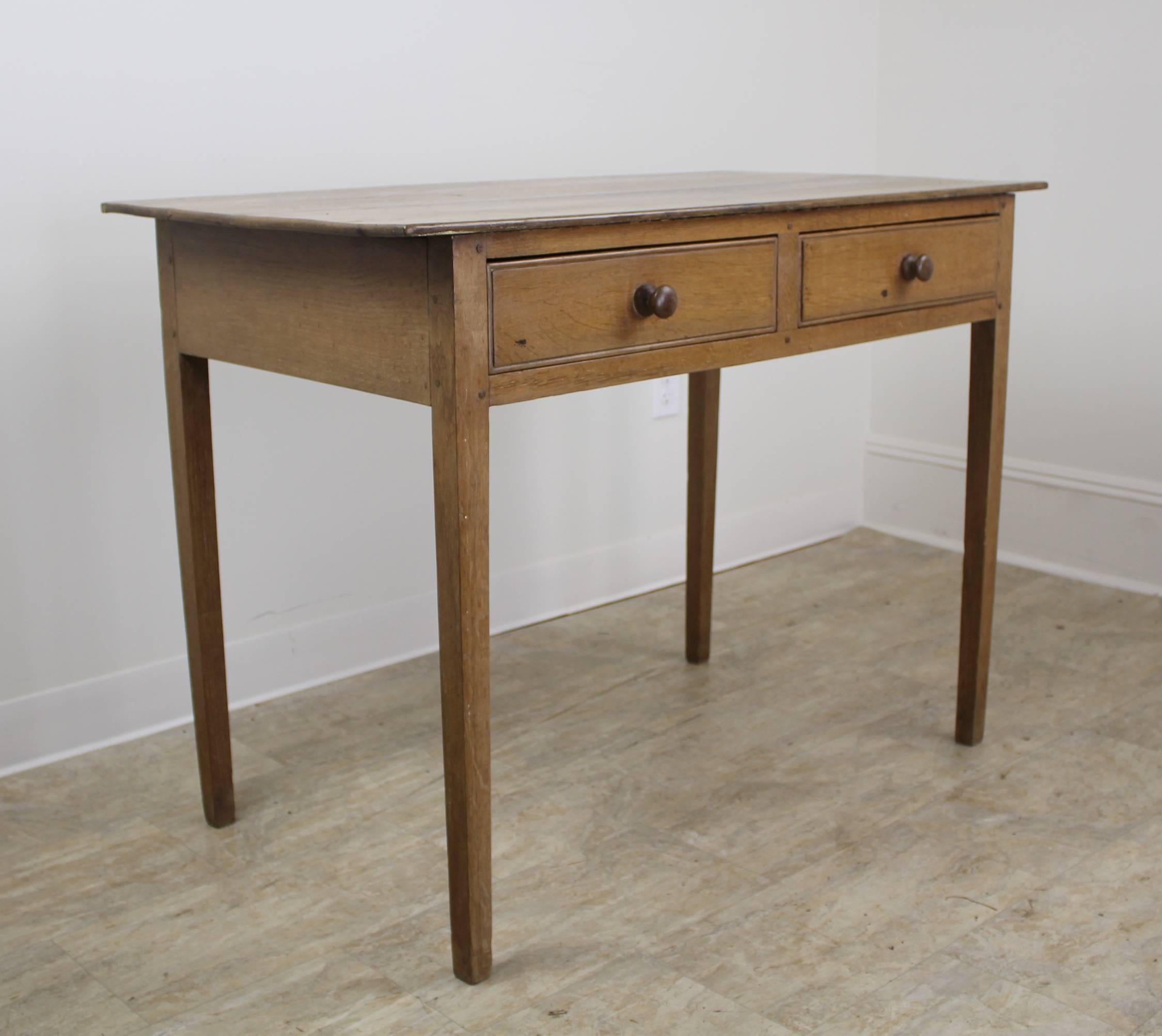 A charming desk or writing table in pickled beechwood. Two roomy drawers make this appropriate for the study or office, or in a casual living space. The pickled wood gives the piece a muted tone which blends into any look. There are some faded 19th