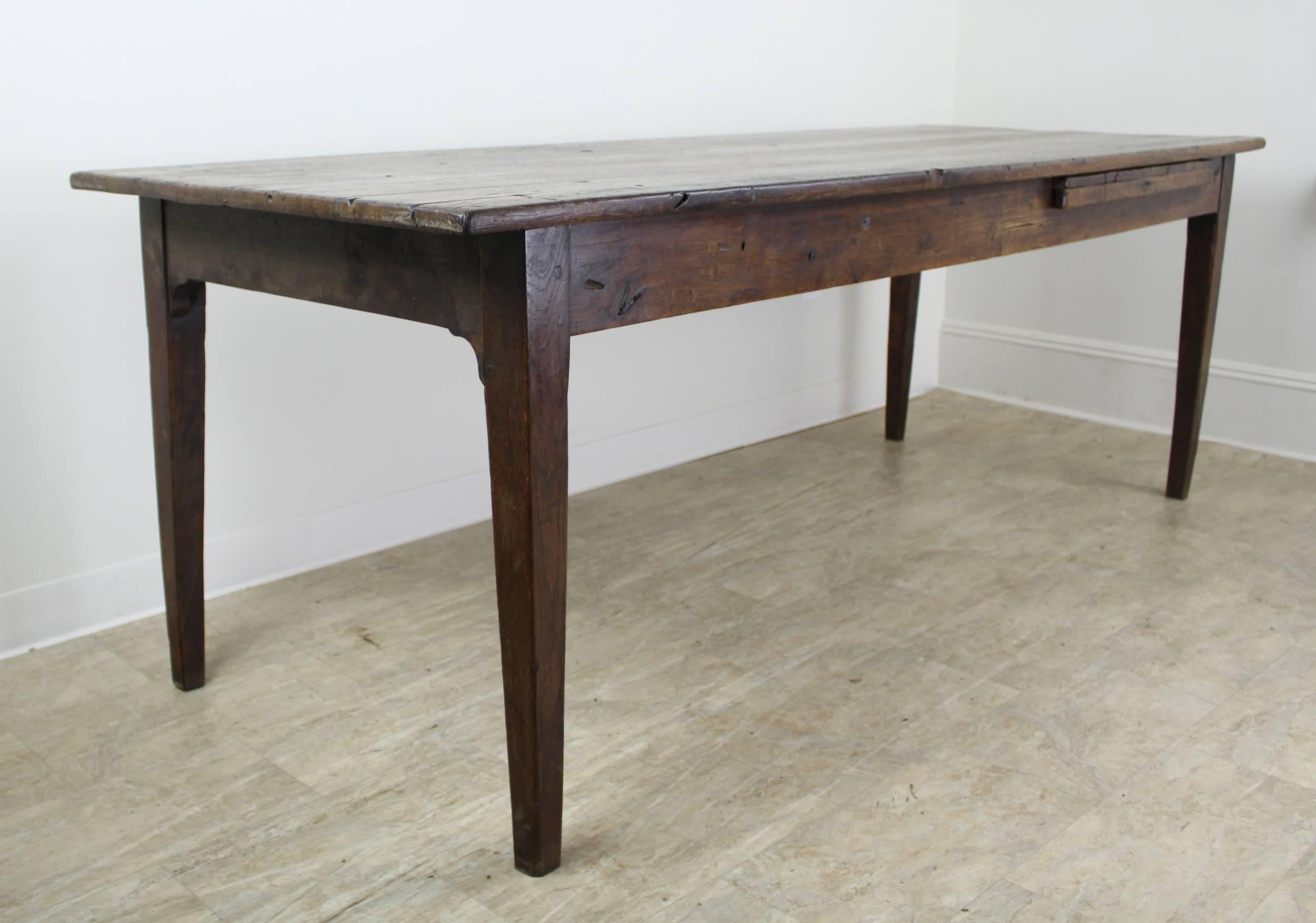 A generously proportioned oak farm table with great character and an interesting bread slide on one slide. Wonderful color and good antique patina. The apron height of 24.5 inches is good for knees. 74 inches between the legs on the long side