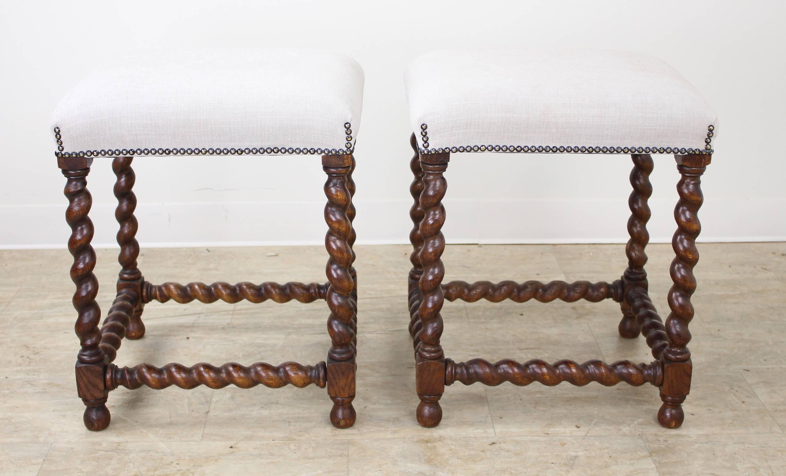 A charming pair of oak barley twist stools, newly upholstered in French linen. Highly decorative!