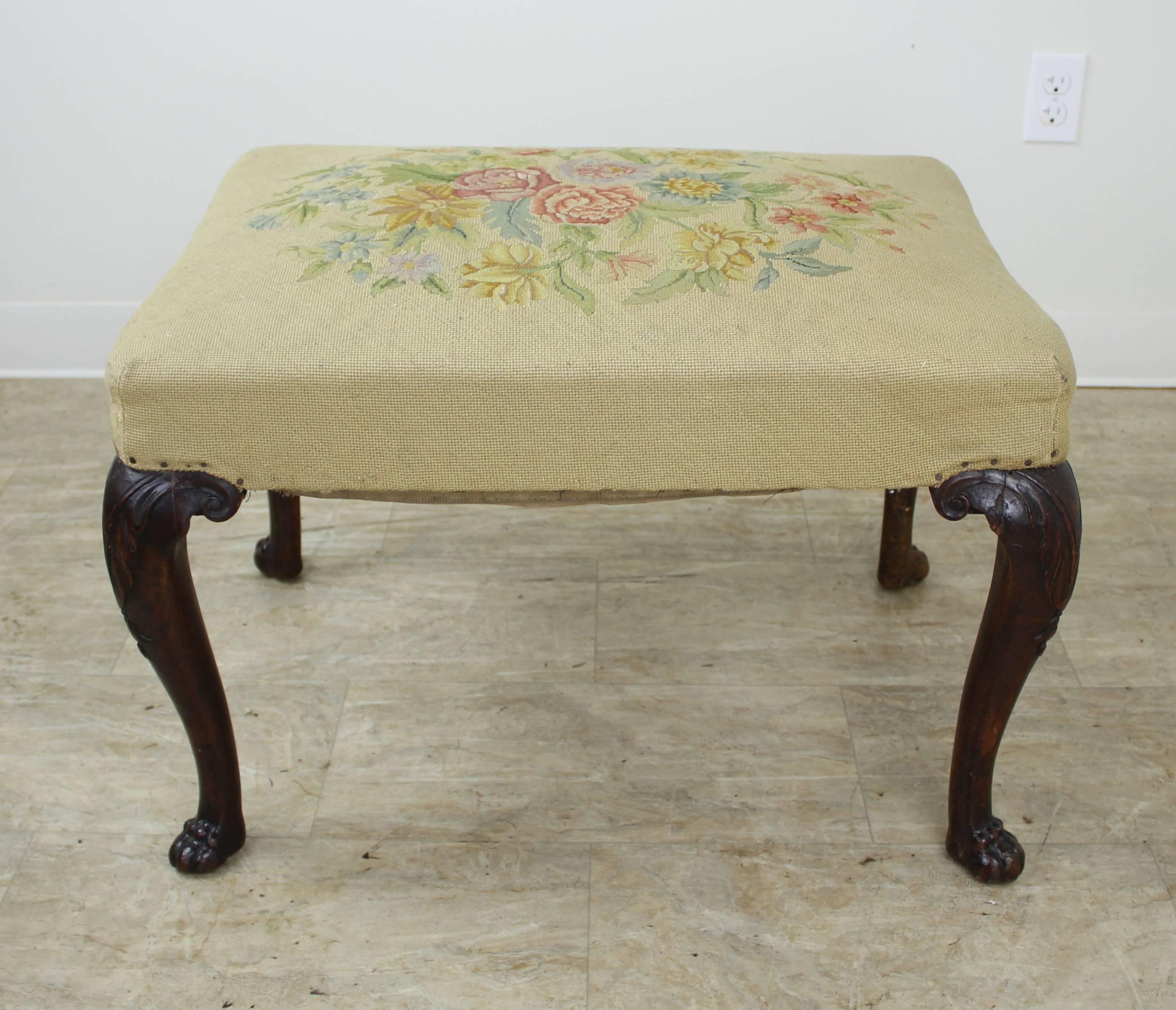 A decorative footstool with its original intricately embroidered seat and finely carved mahogany legs. The claw feet on this piece are particularly well articulated. The seat has good loft for a piece of its age. Sturdy and would make a nice