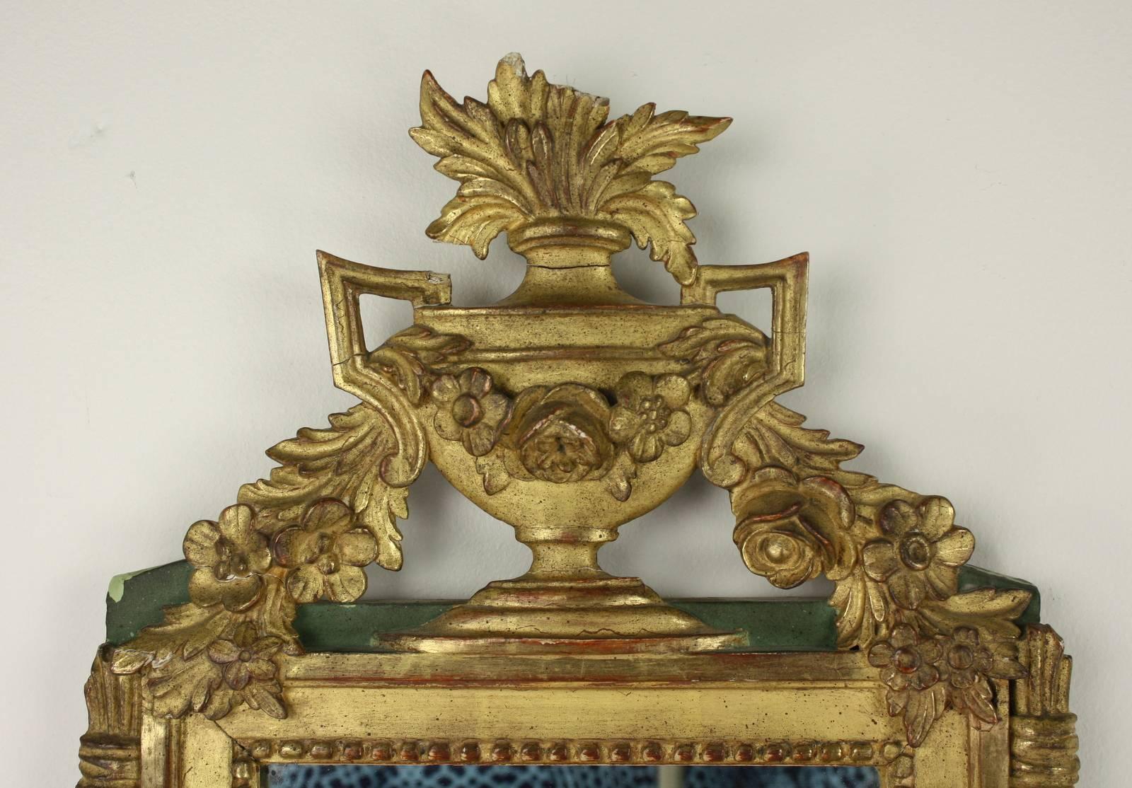 A beautiful mid 19th Century carved and gilded French wall mirror in the shape of a classical vase and floral garland.  The glass, though later, is also 19th century.  There are some small chips and old repairs which we feel adds to the character