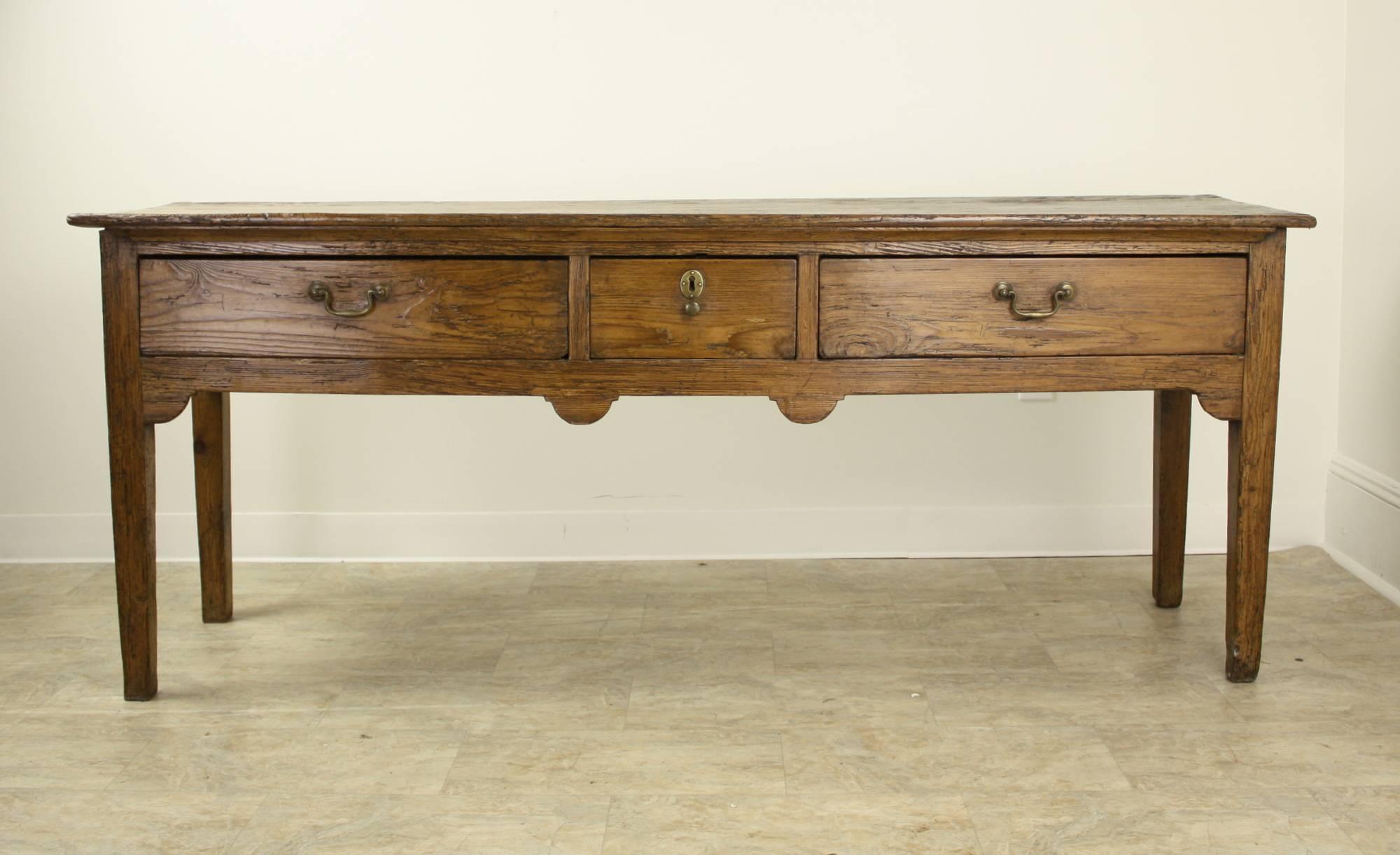 A handsome long pine console or sideboard with wonderful honey color and patina highlighted by exceptional grain.  The charming carved apron completes the look.  30
